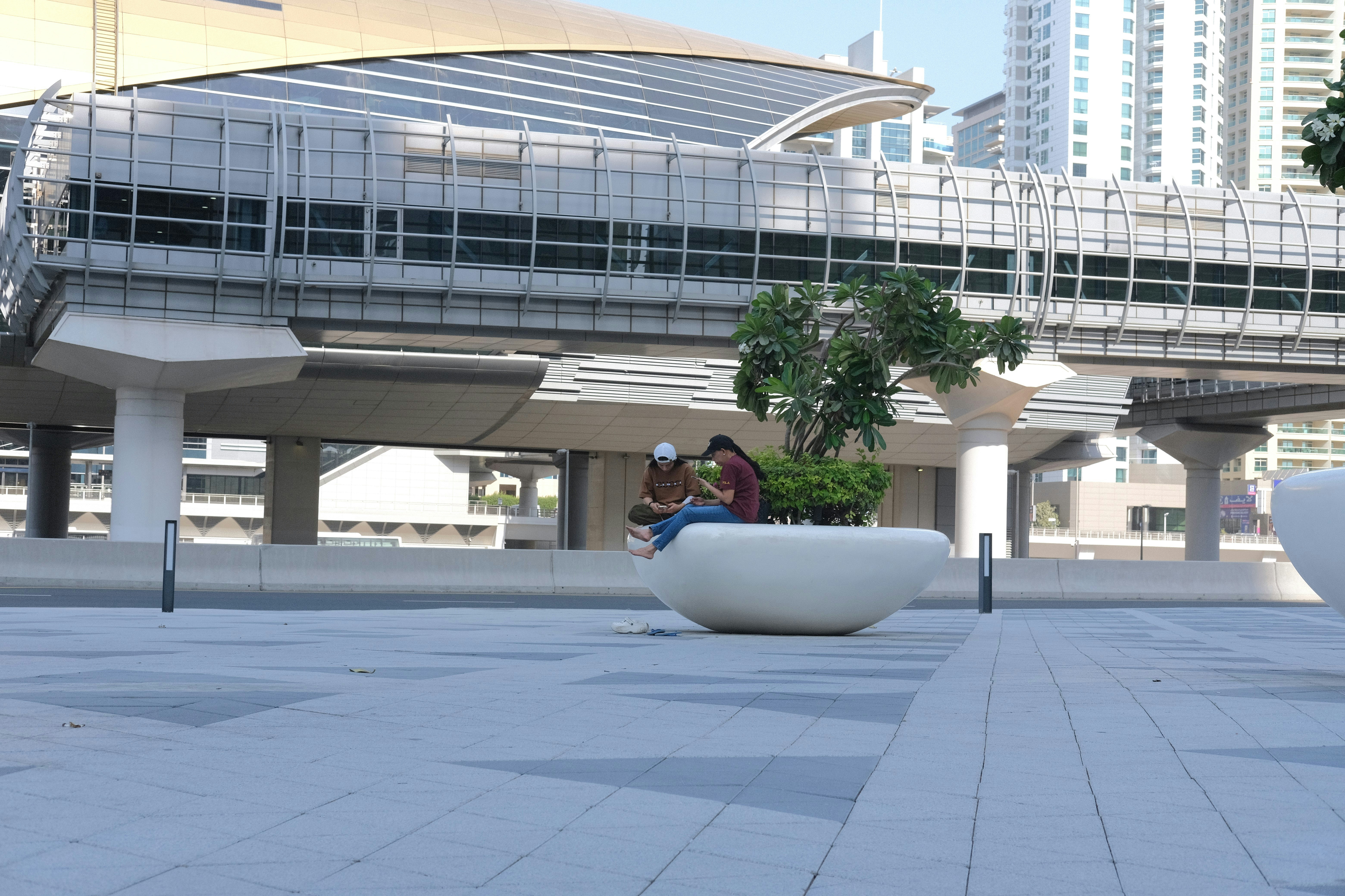 Two people sitting on a modern bench outdoors.