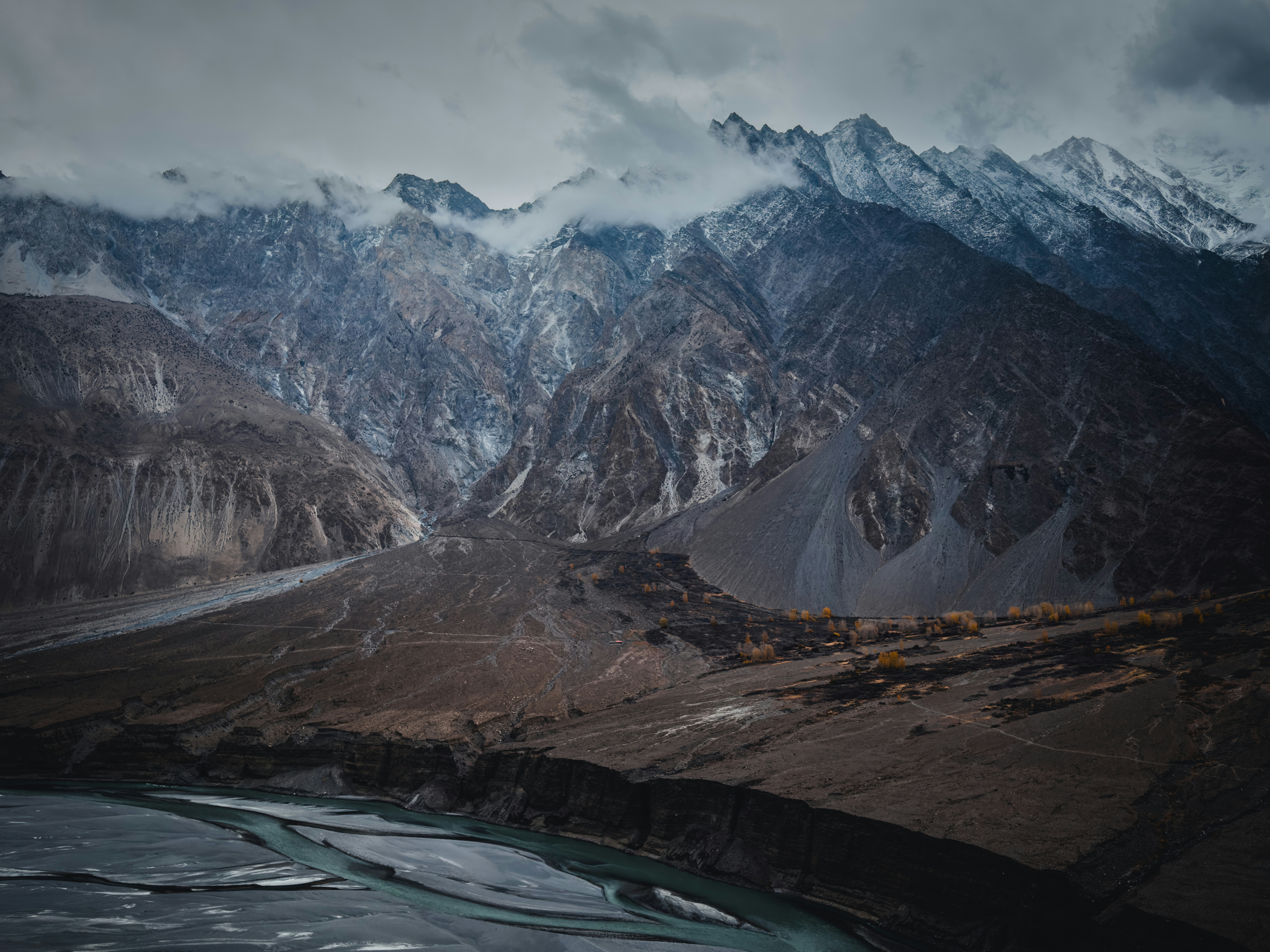 Snow-capped mountains and a winding river under cloudy skies.