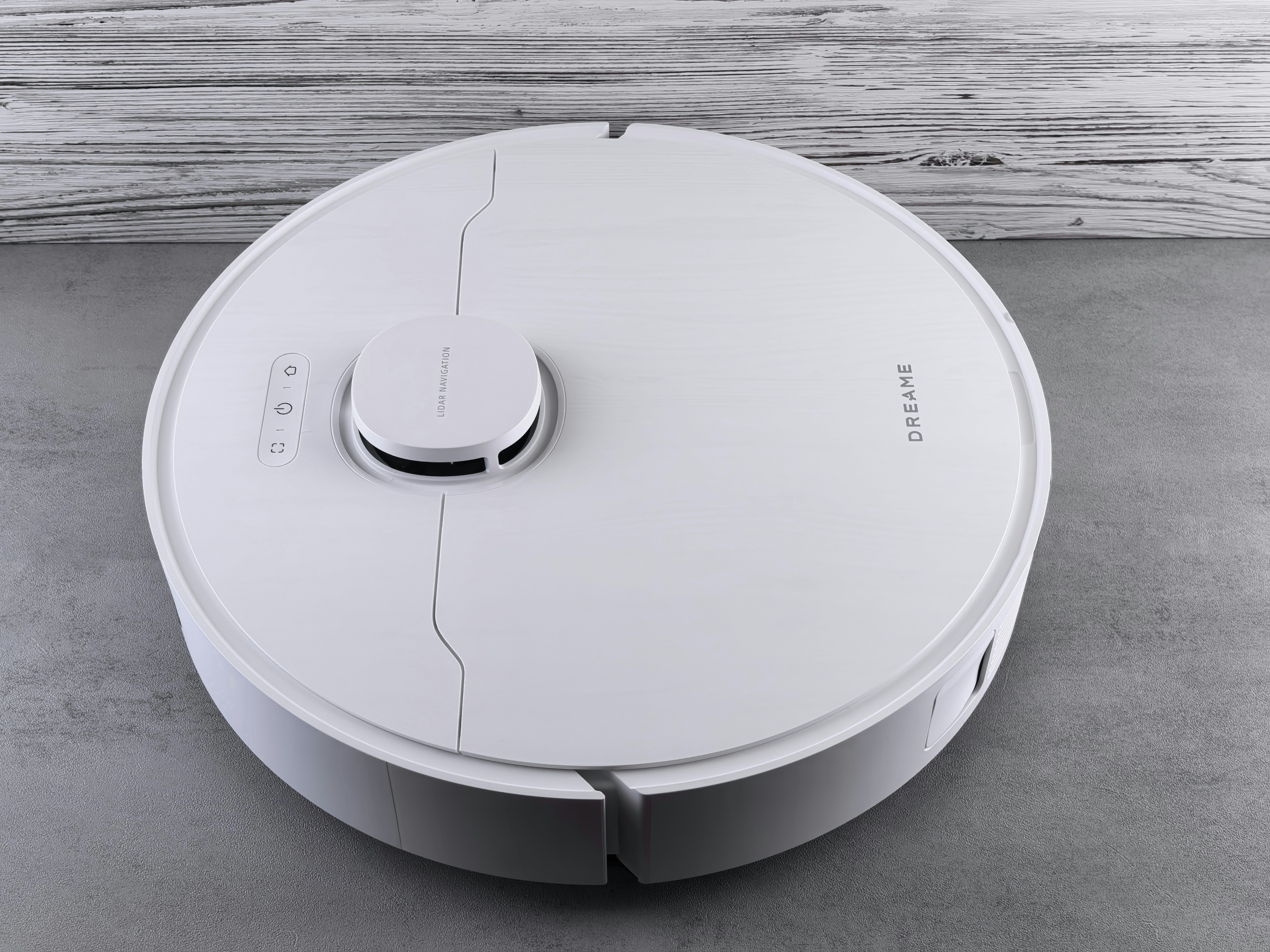 A white robot vacuum cleaner on a grey floor.
