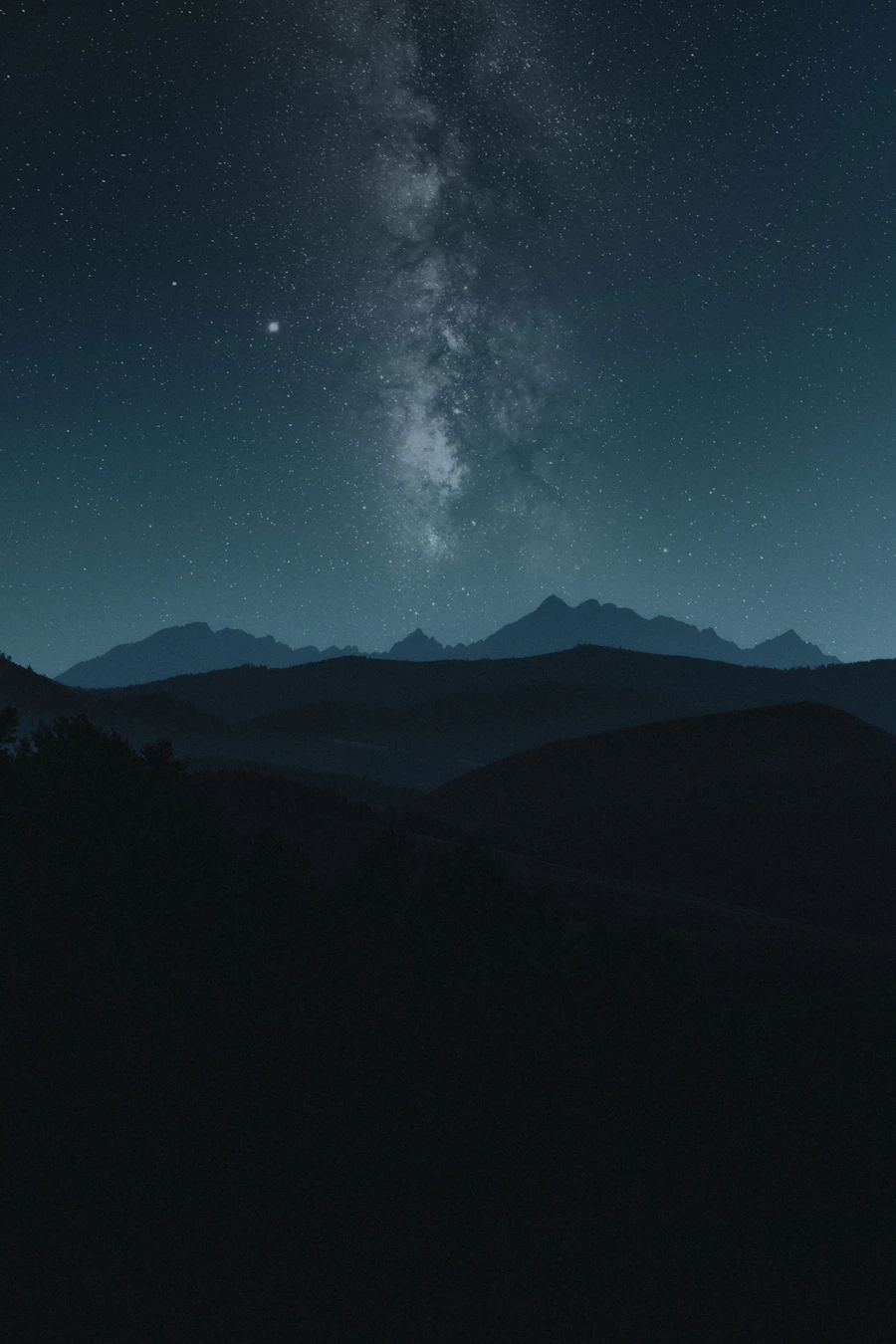 Starry night sky over silhouetted Rocky Mountain peaks