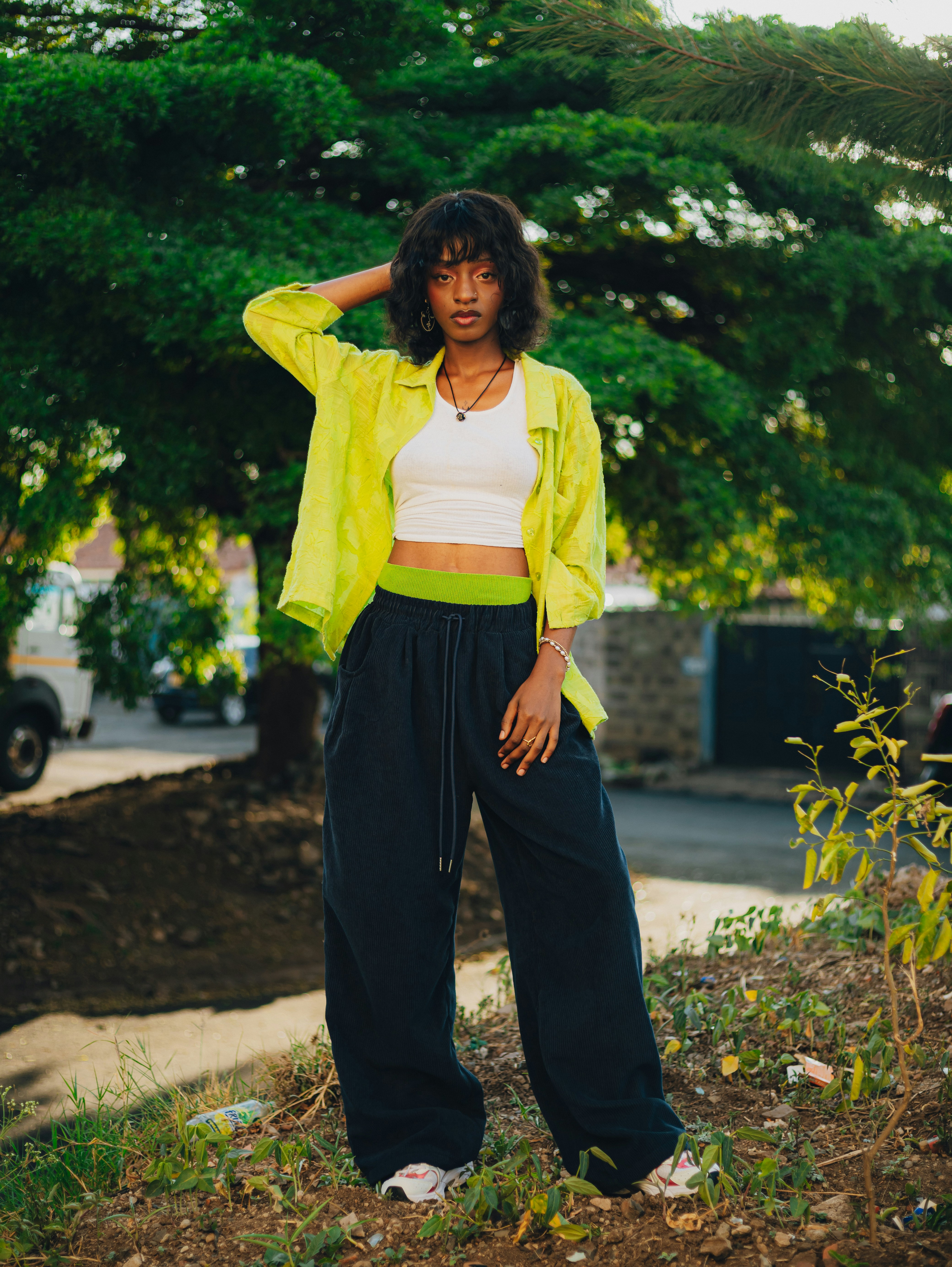 A woman stands outdoors in front of a large tree.