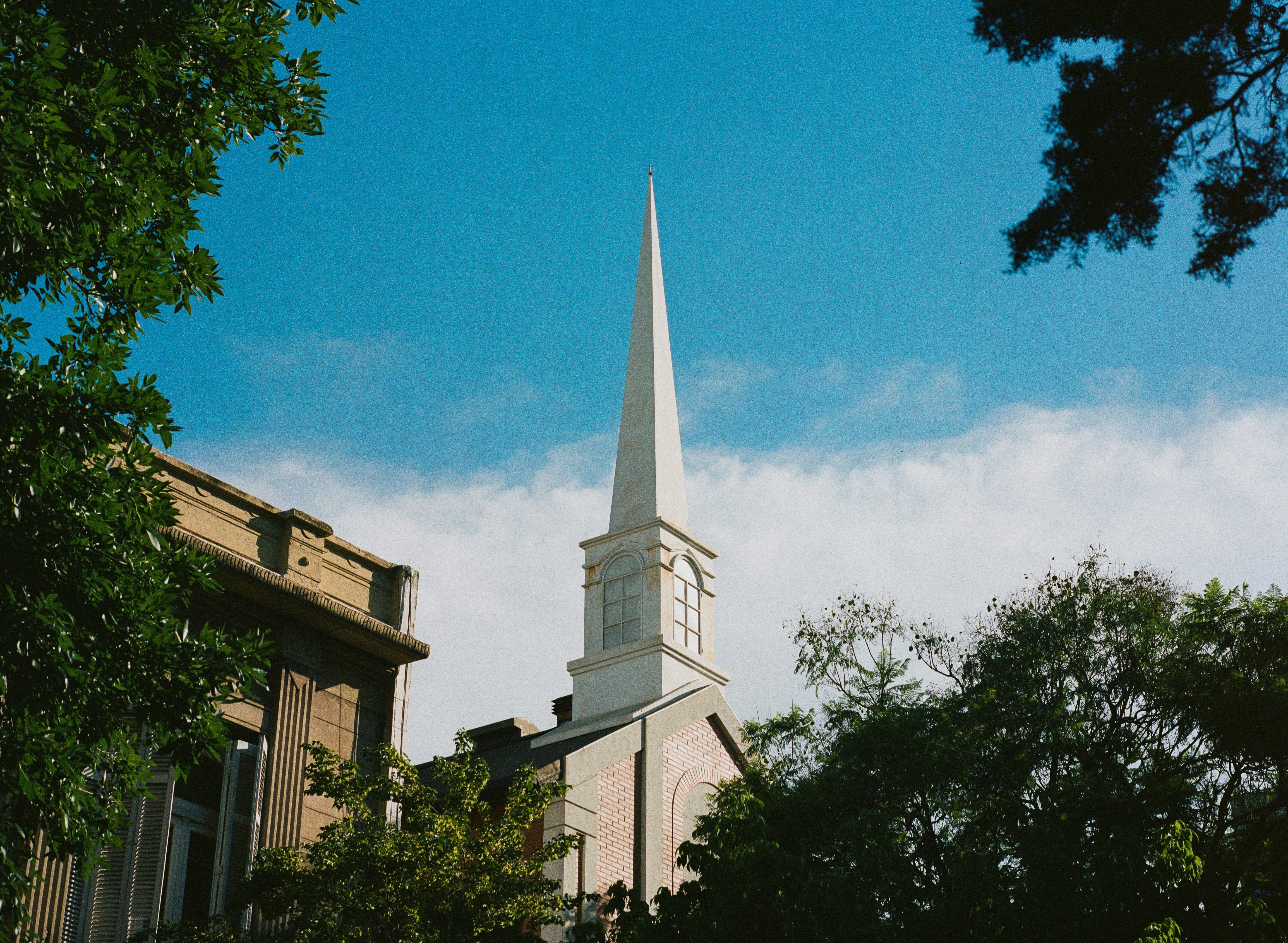 Weißer Kirchturm vor blauem Himmel.
