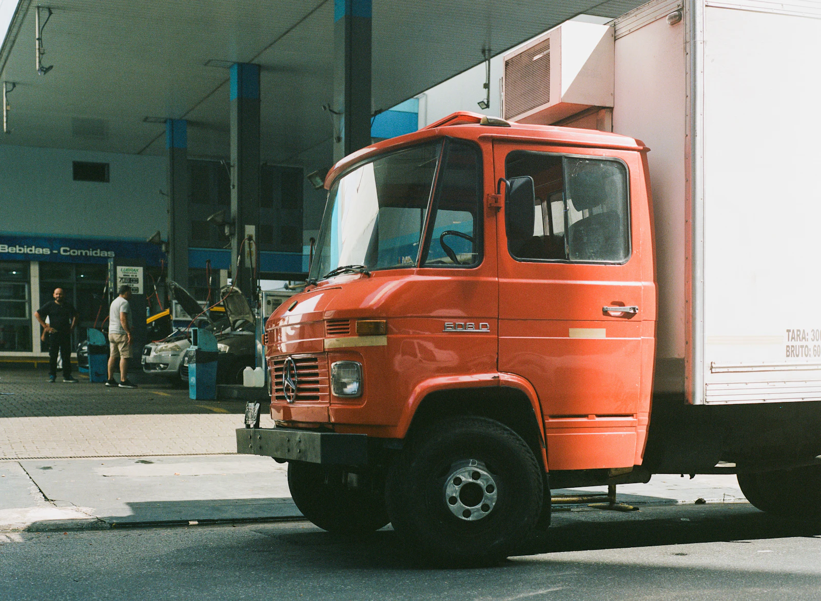 An orange truck parked at a filling station