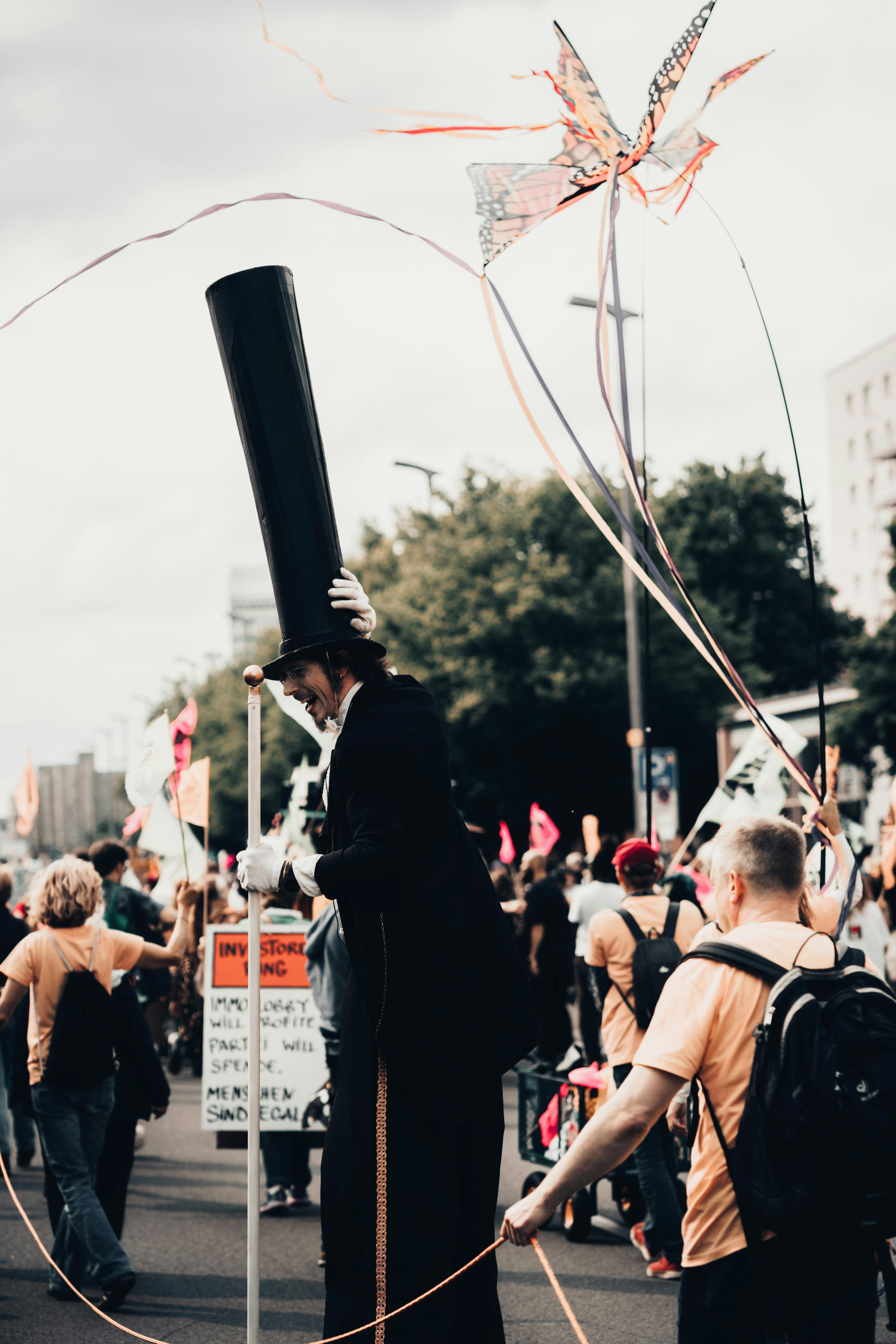 Man in top hat walks in parade with kite