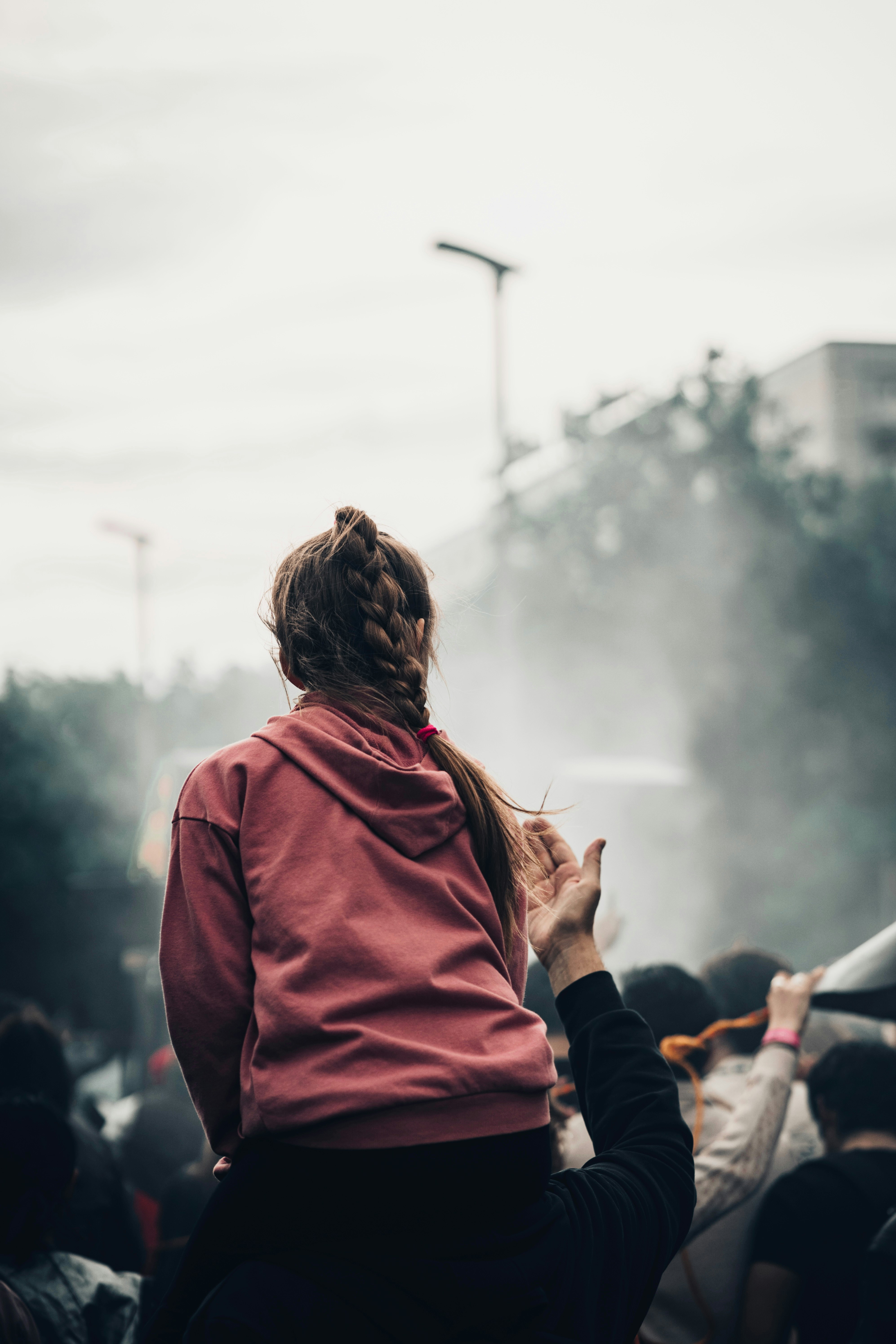 Girl with braided hair on shoulders watching event