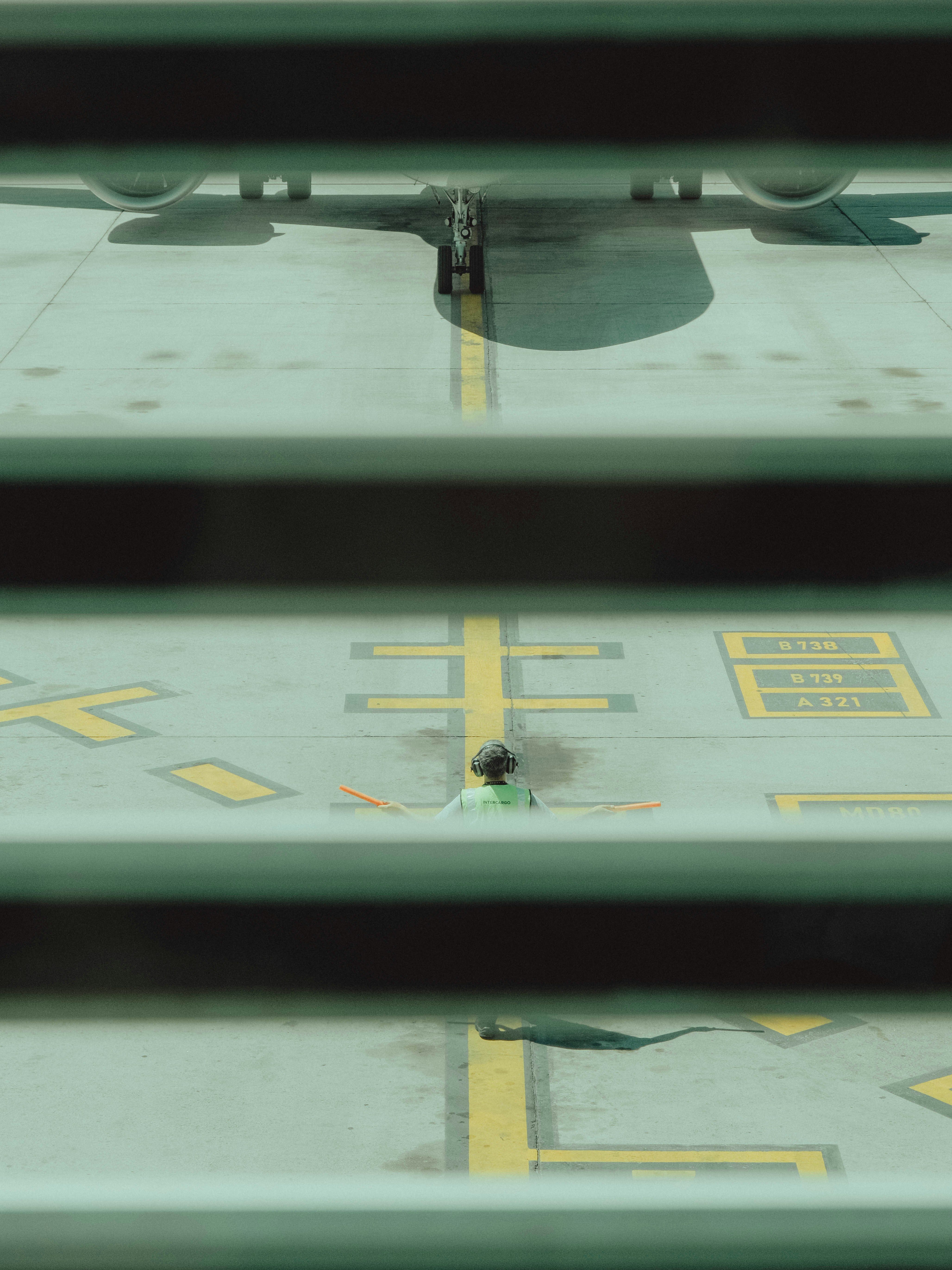 An airplane on the tarmac viewed through blinds.