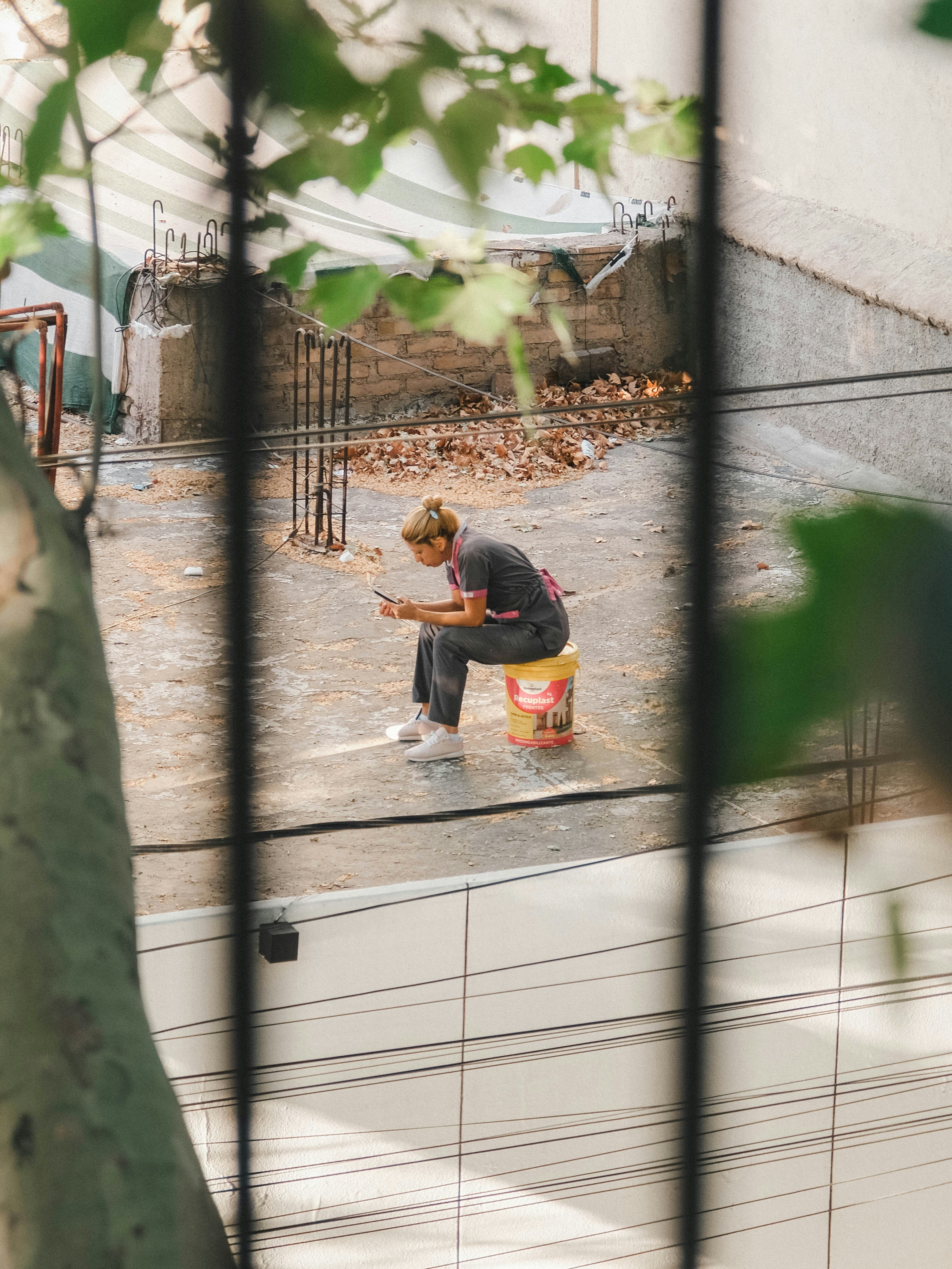 Frau sitzt auf einem Eimer auf der Baustelle