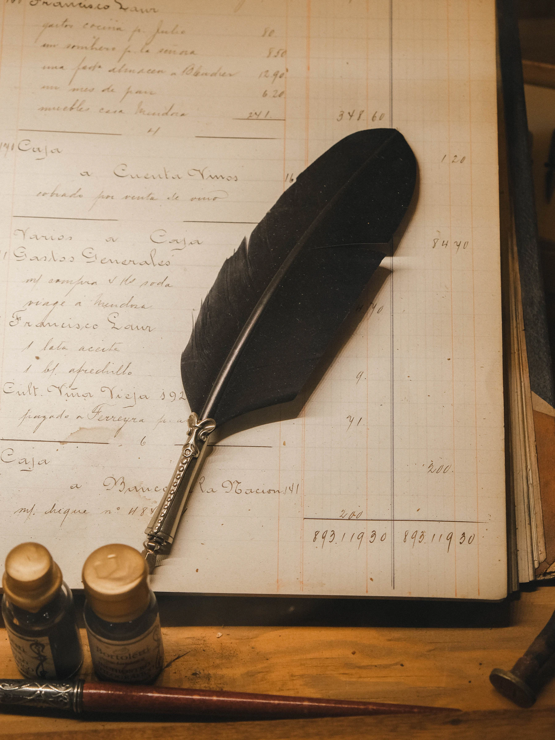 A feather quill pen resting beside ink bottles on an old ledger, evoking colonial-era correspondence
