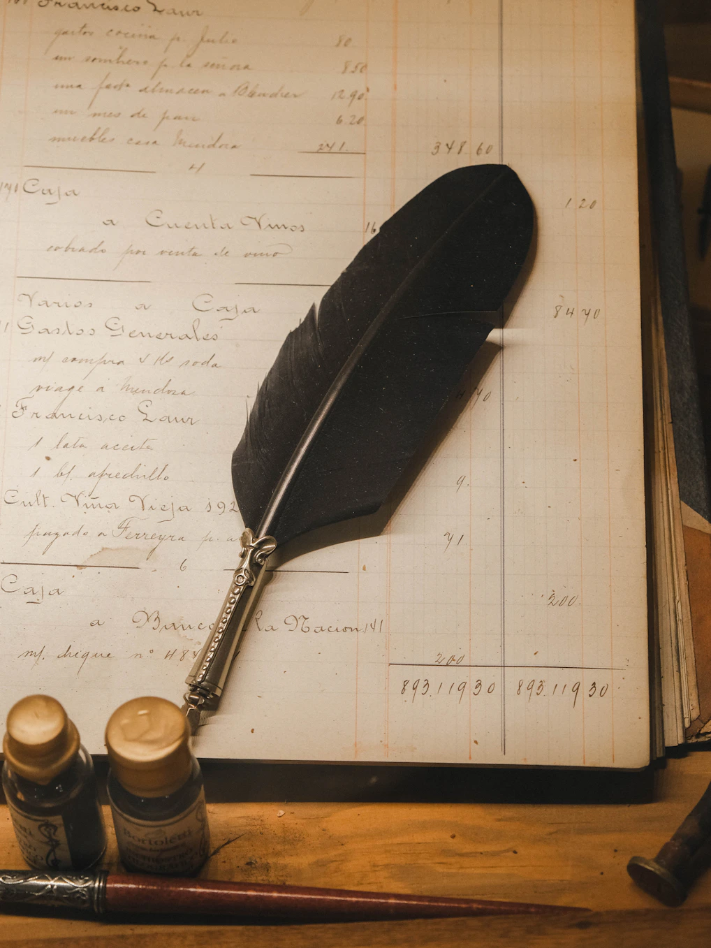 Feather quill pen with ink bottles on old ledger