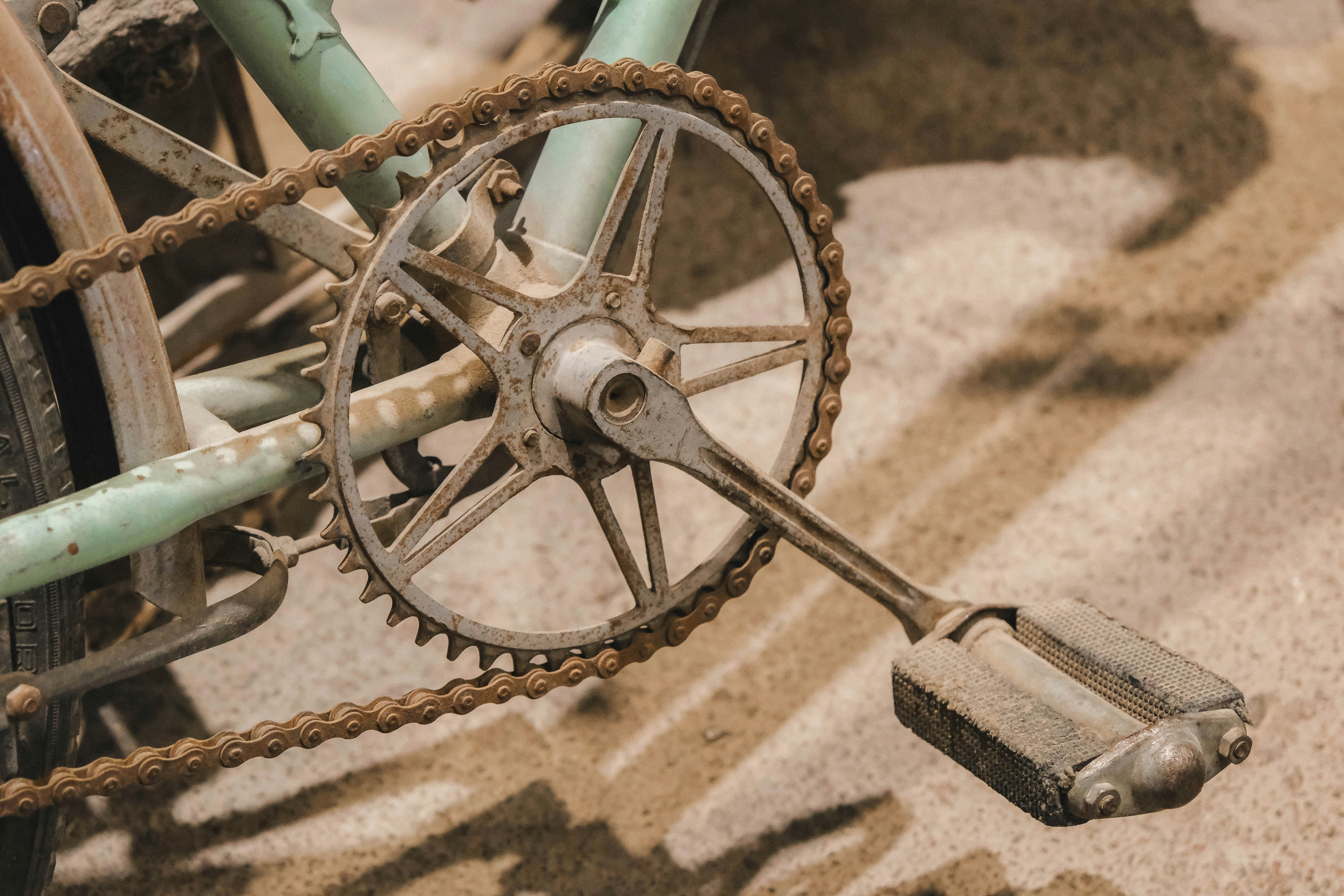 Primer plano de un pedal y cadena de bicicleta oxidados