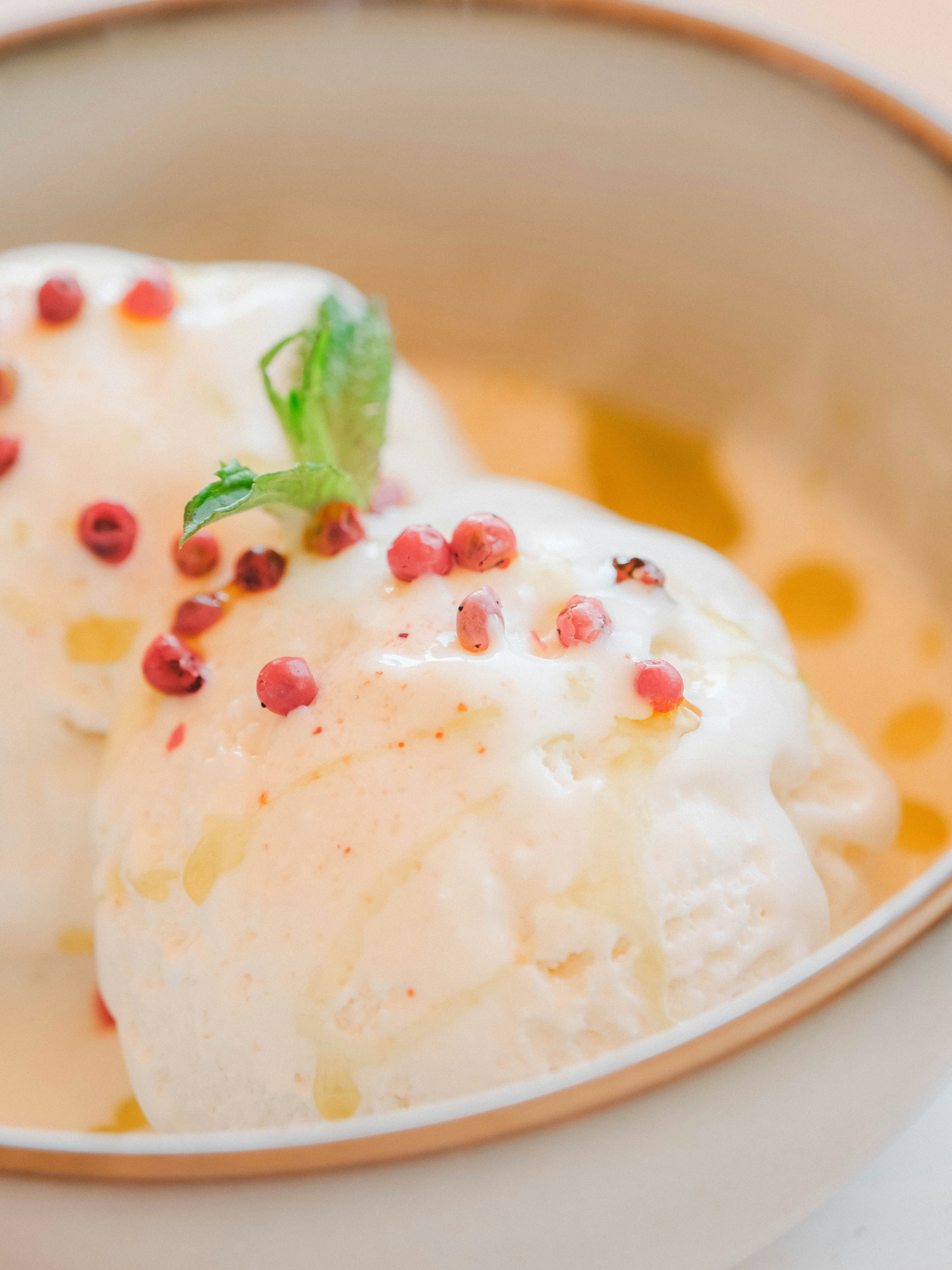 Two scoops of vanilla ice cream with pink peppercorns.