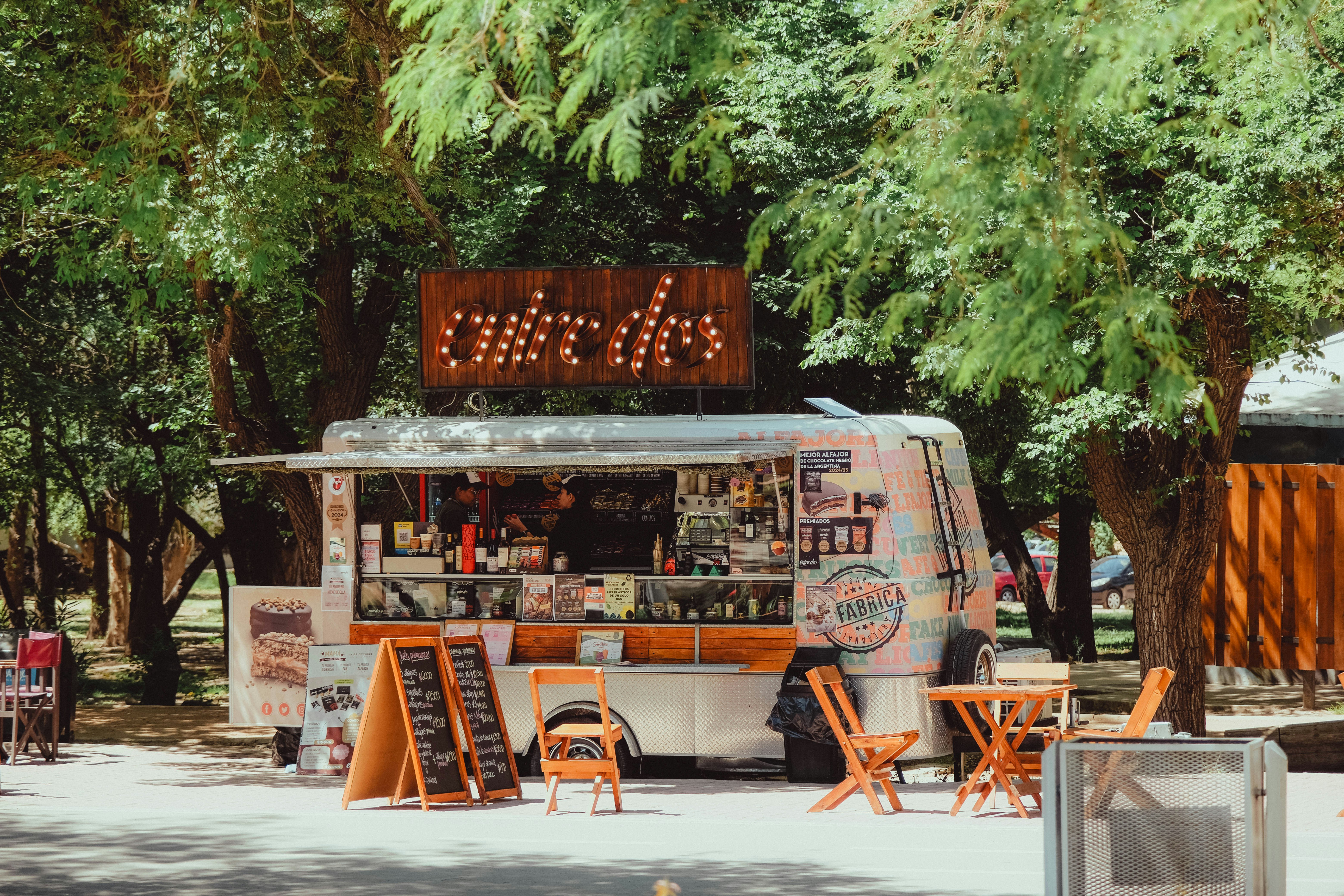 Food Truck mit Außensitzplätzen unter Bäumen