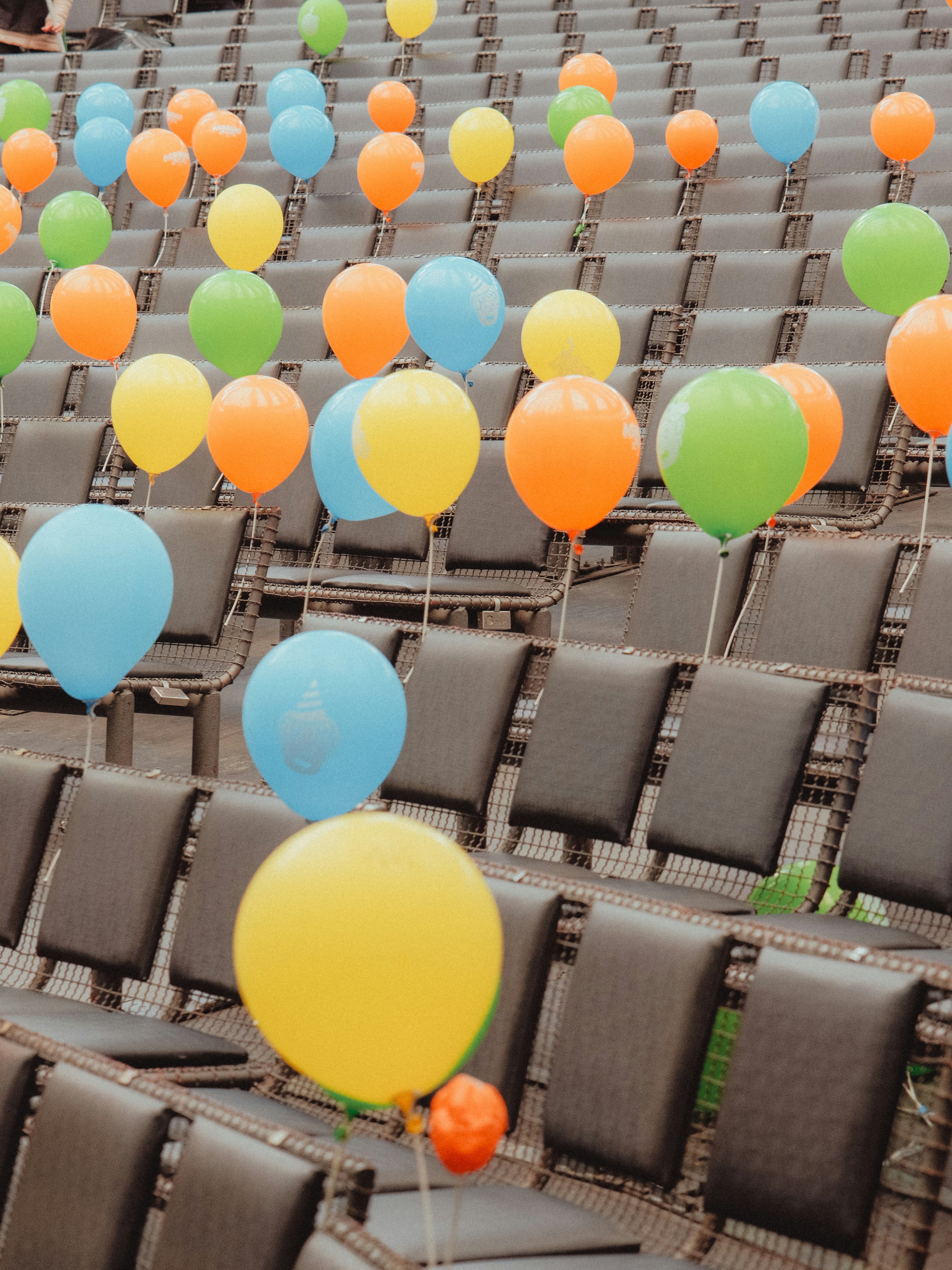 Des rangées de ballons colorés sur des sièges vides.