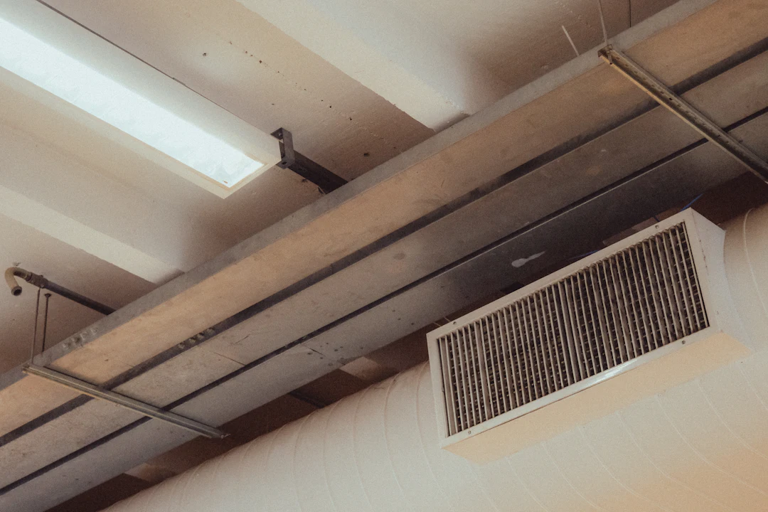Ceiling-mounted supply air register beside exposed beams and lighting