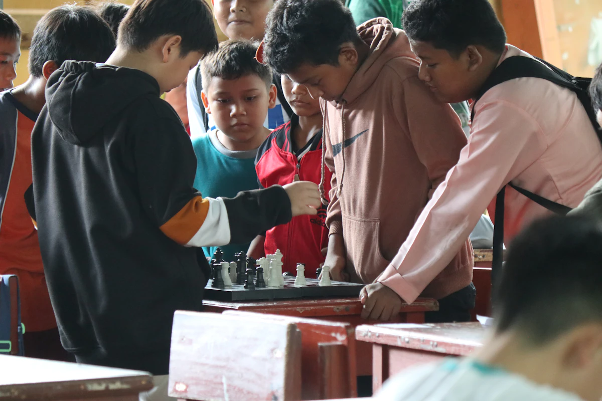 Teenagers gathered around a chess board in a classroom