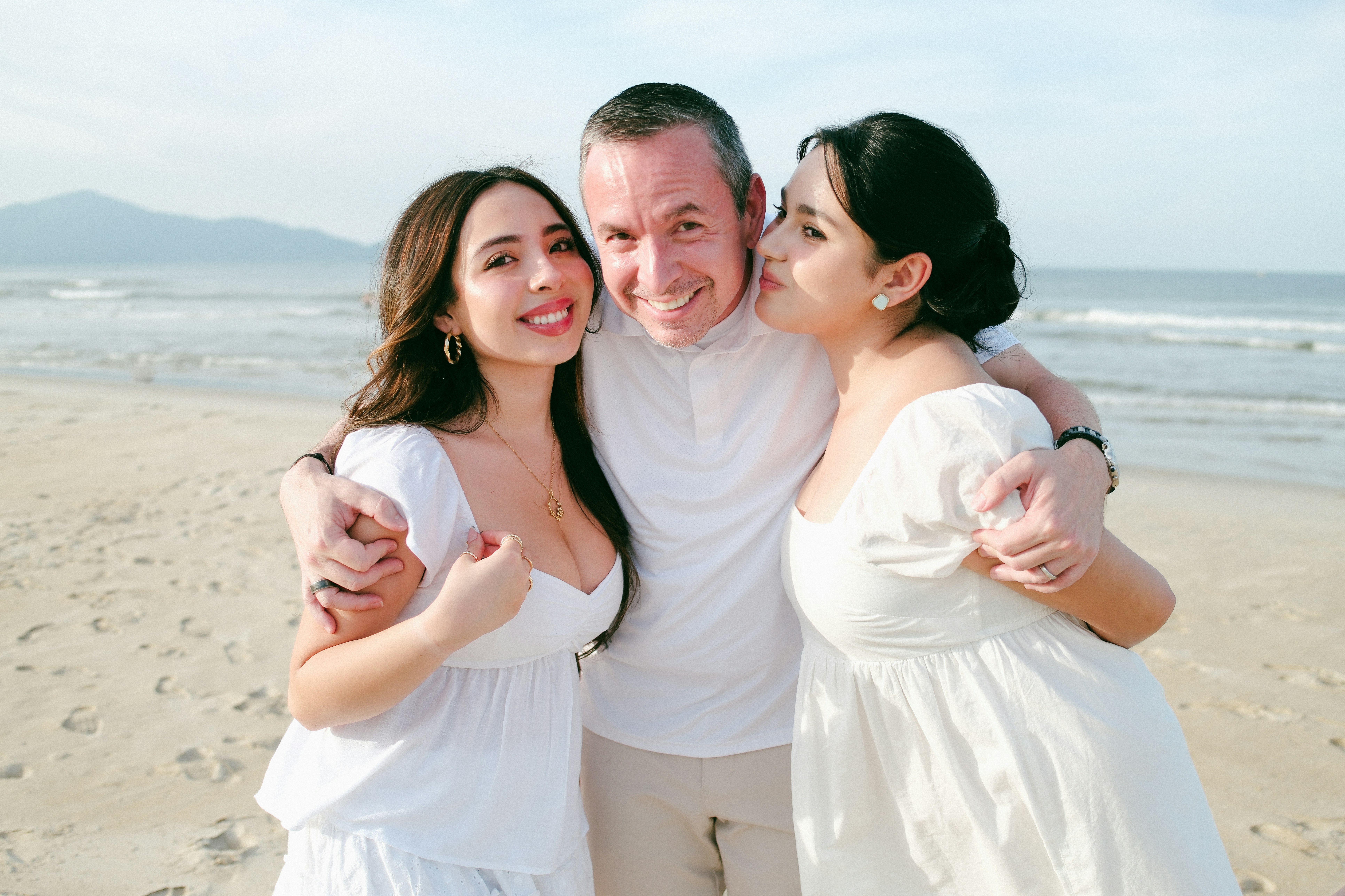 Couple and daughter embracing on a beach.