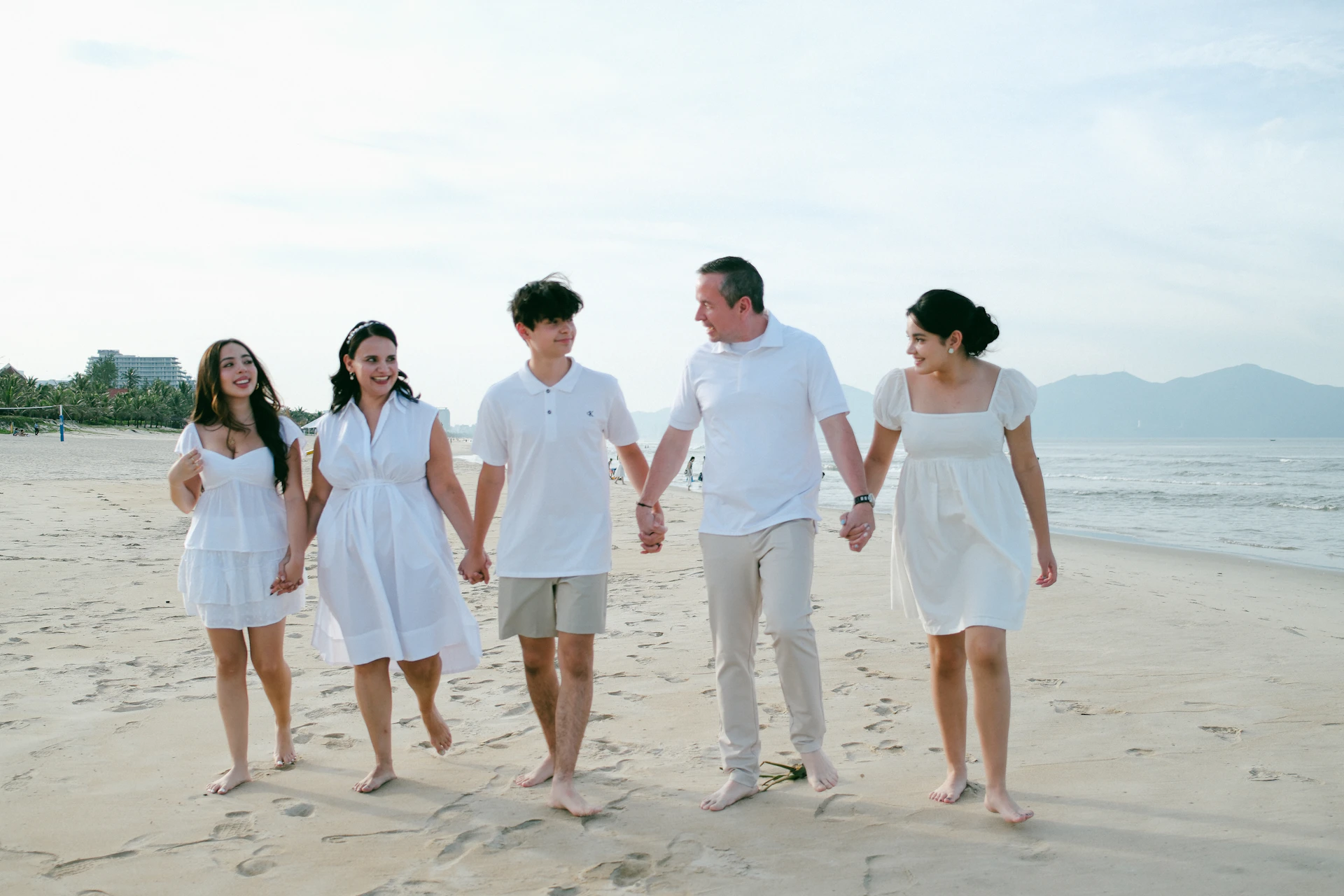 Family walking hand-in-hand on a sandy beach