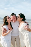 Two women kissing a man on the beach