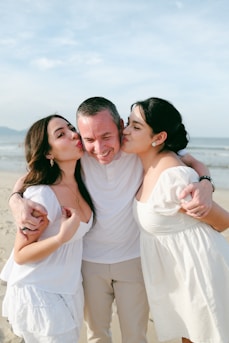 Two women kissing a man on the beach