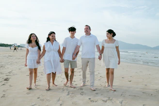 Family walking hand-in-hand on a sandy beach.