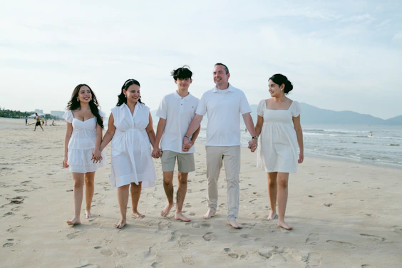 Family walking hand-in-hand on a sandy beach.