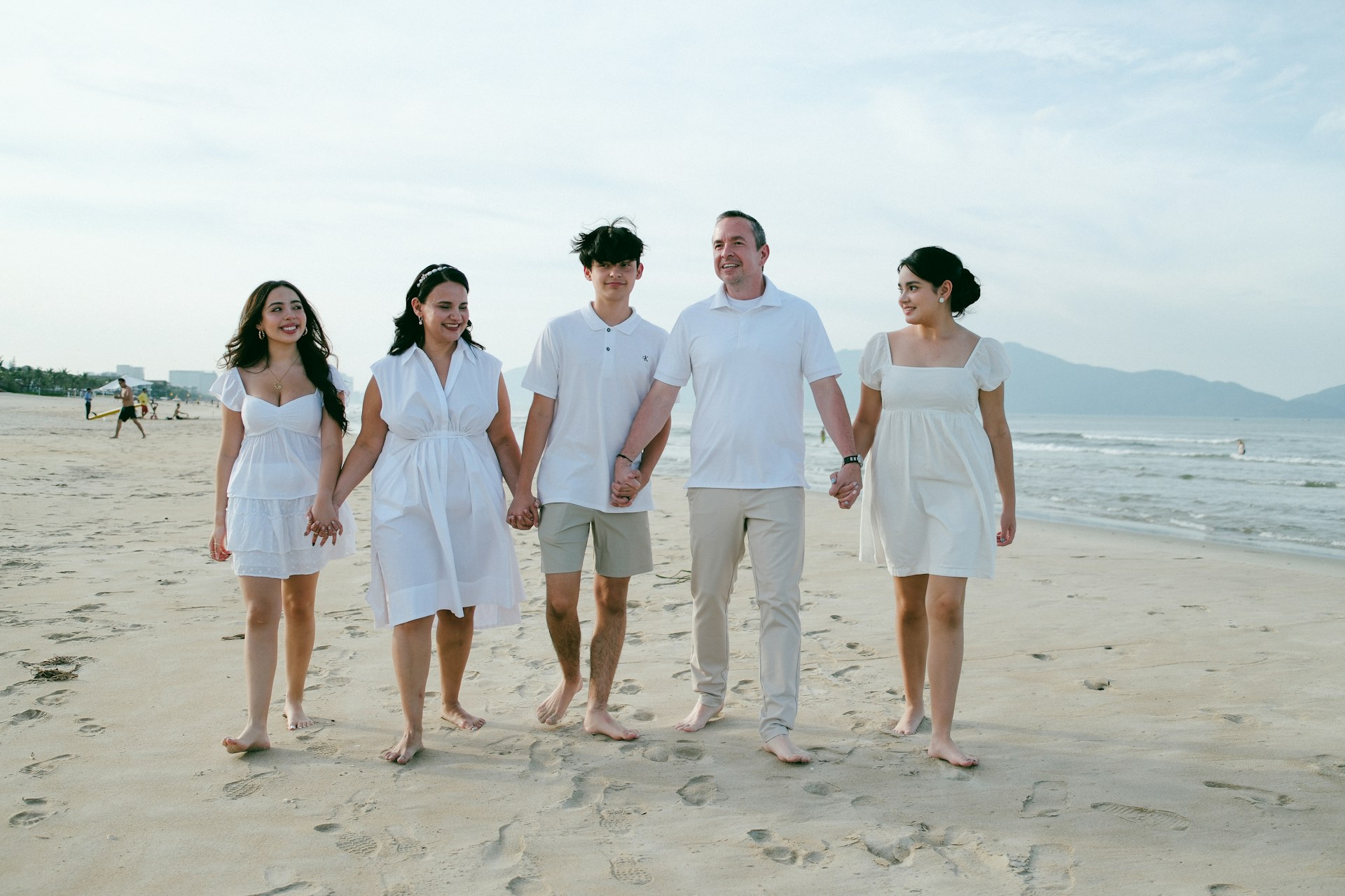 Family walking hand-in-hand on a sandy beach.