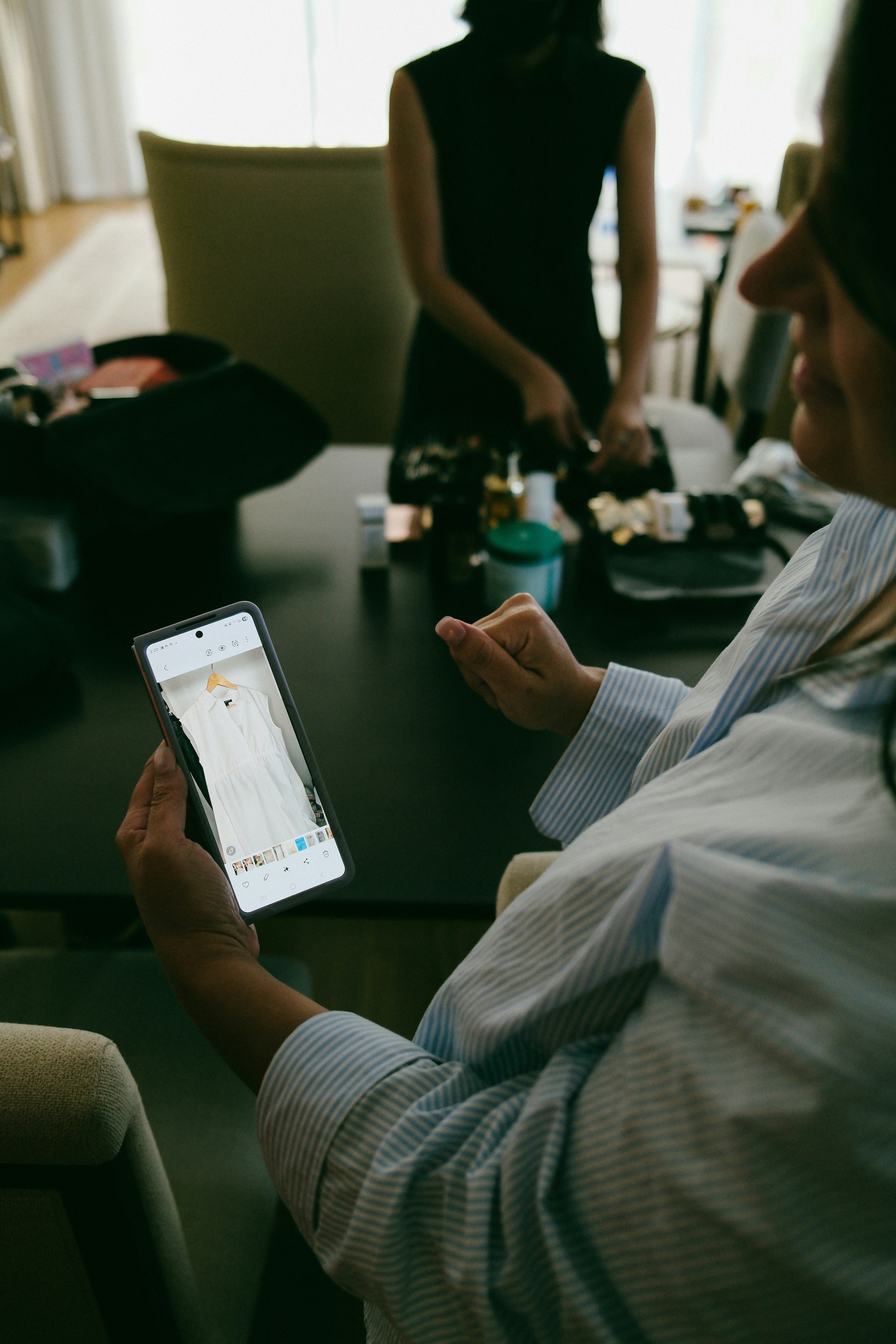 Woman holds phone showing white dress on screen.