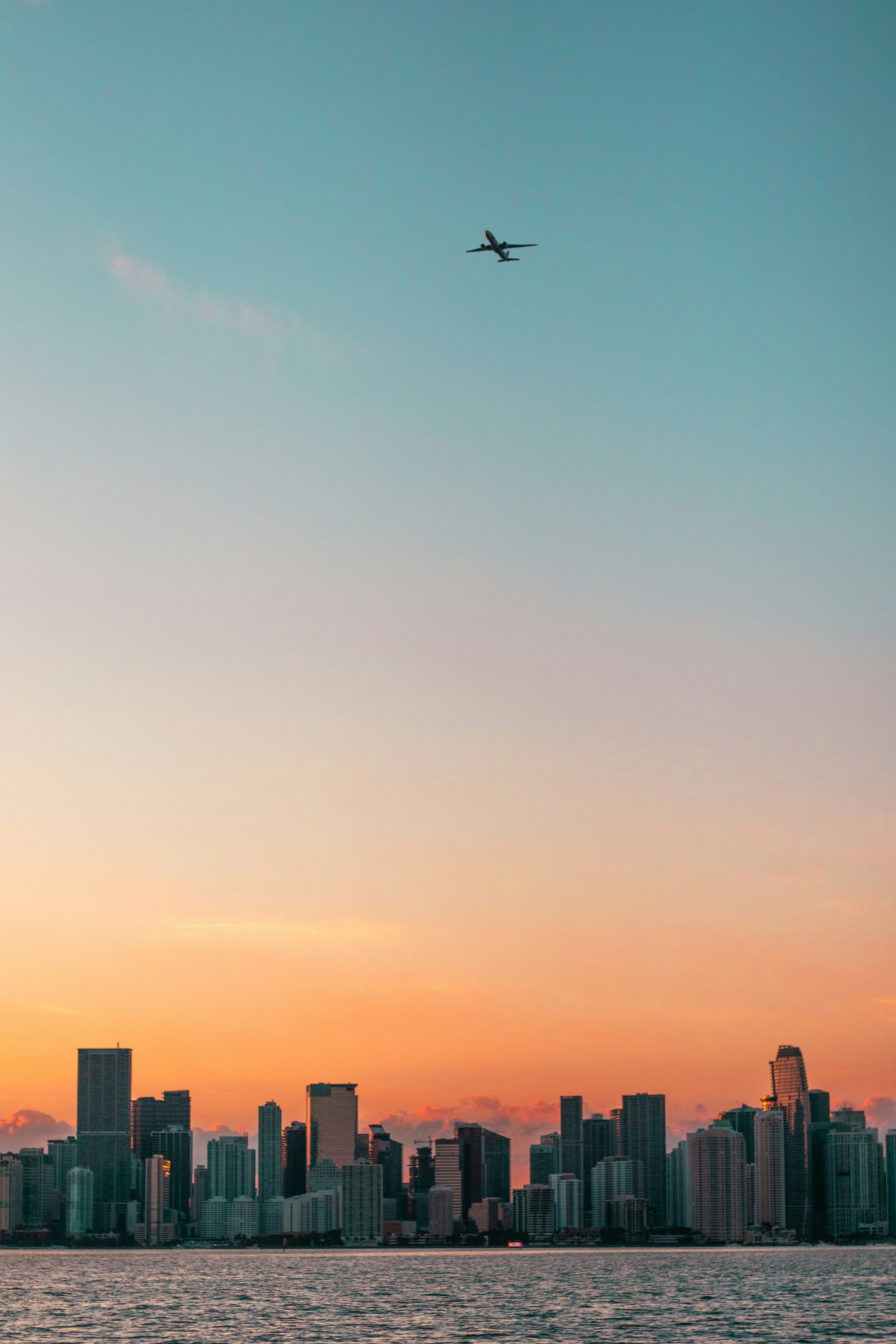 Airplane flying over miami skyline at sunset