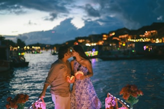 Couple kissing on a boat with lanterns at night.