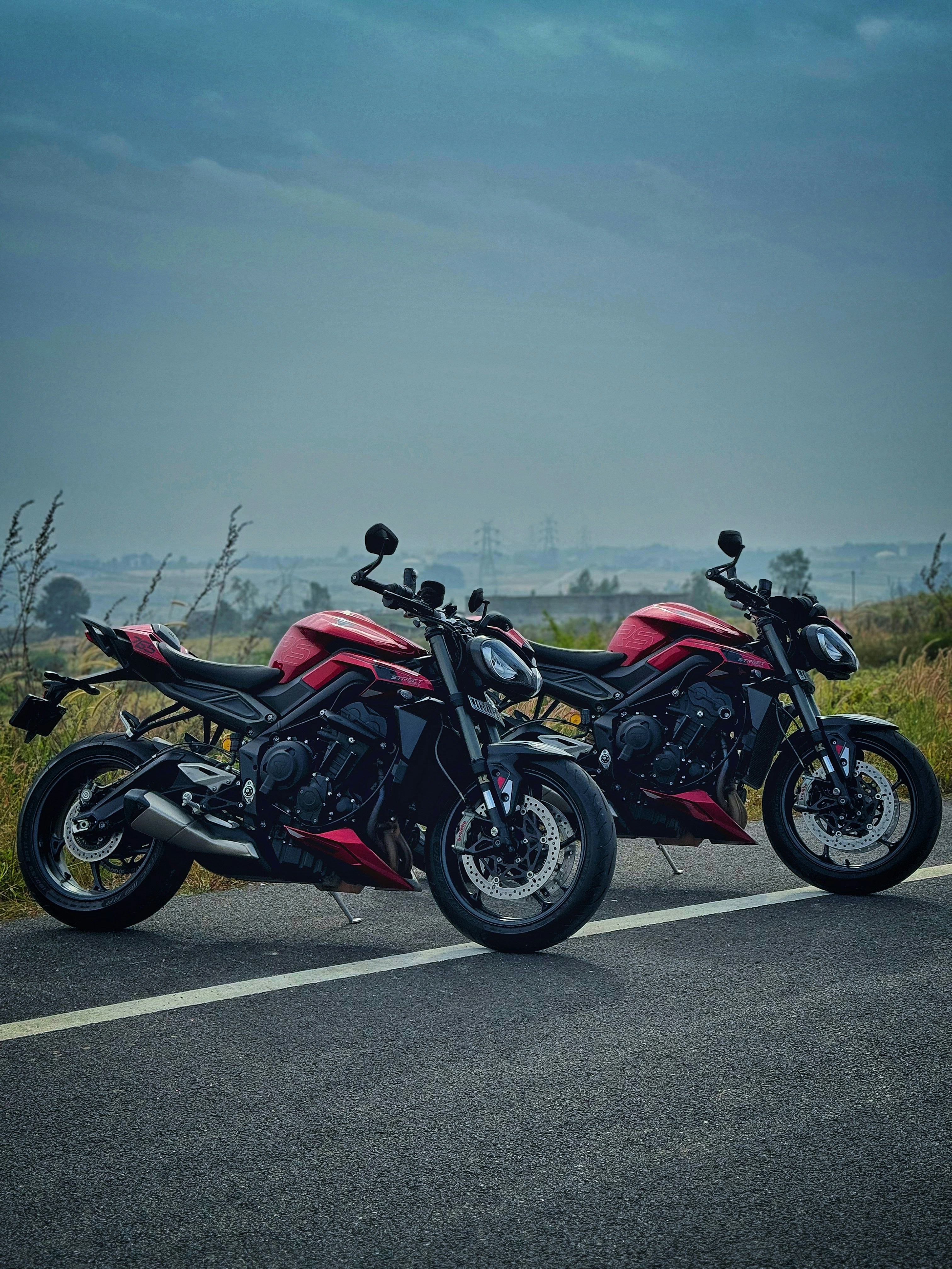 Dua sepeda motor merah diparkir di jalan