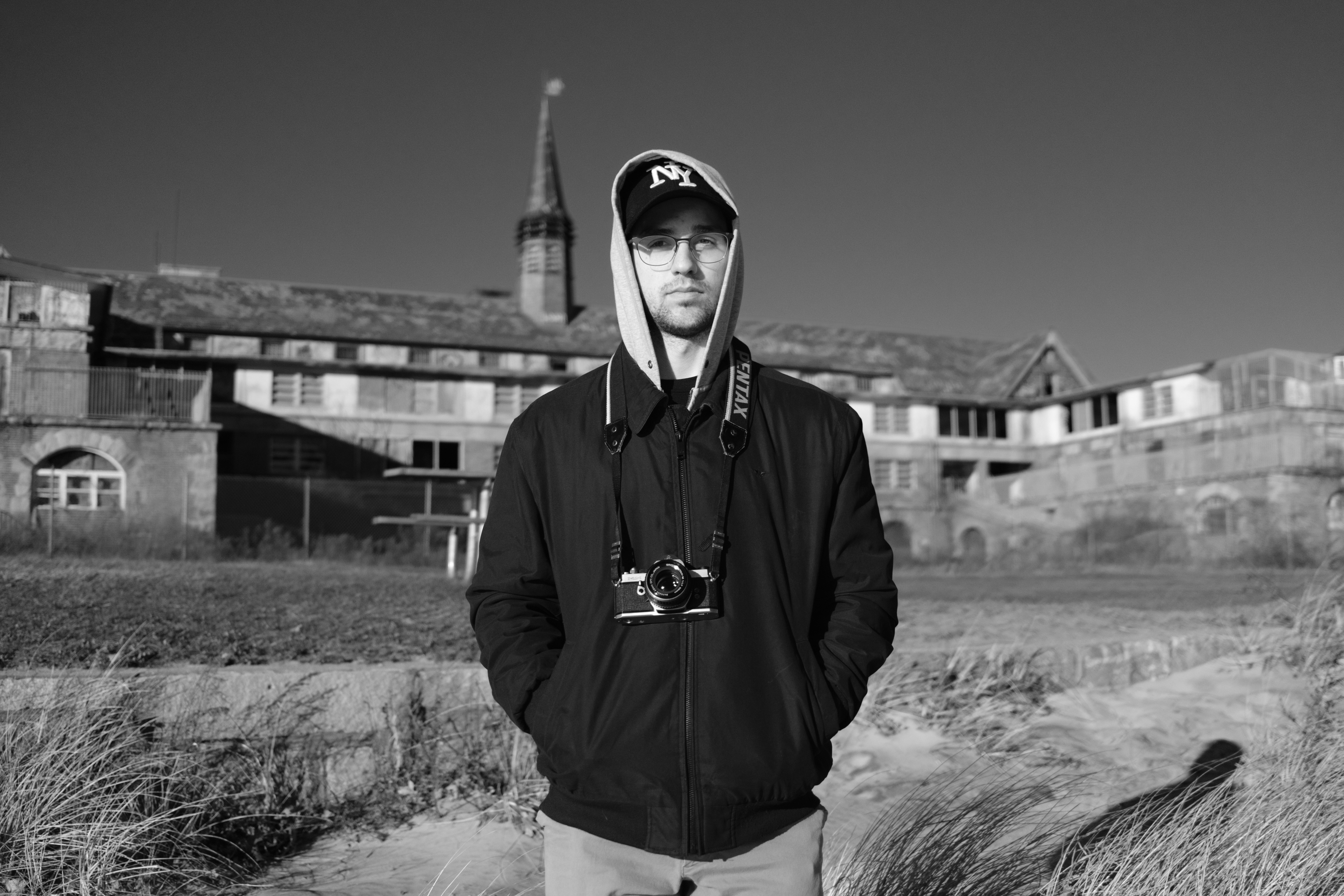 Man in hoodie standing in front of abandoned building
