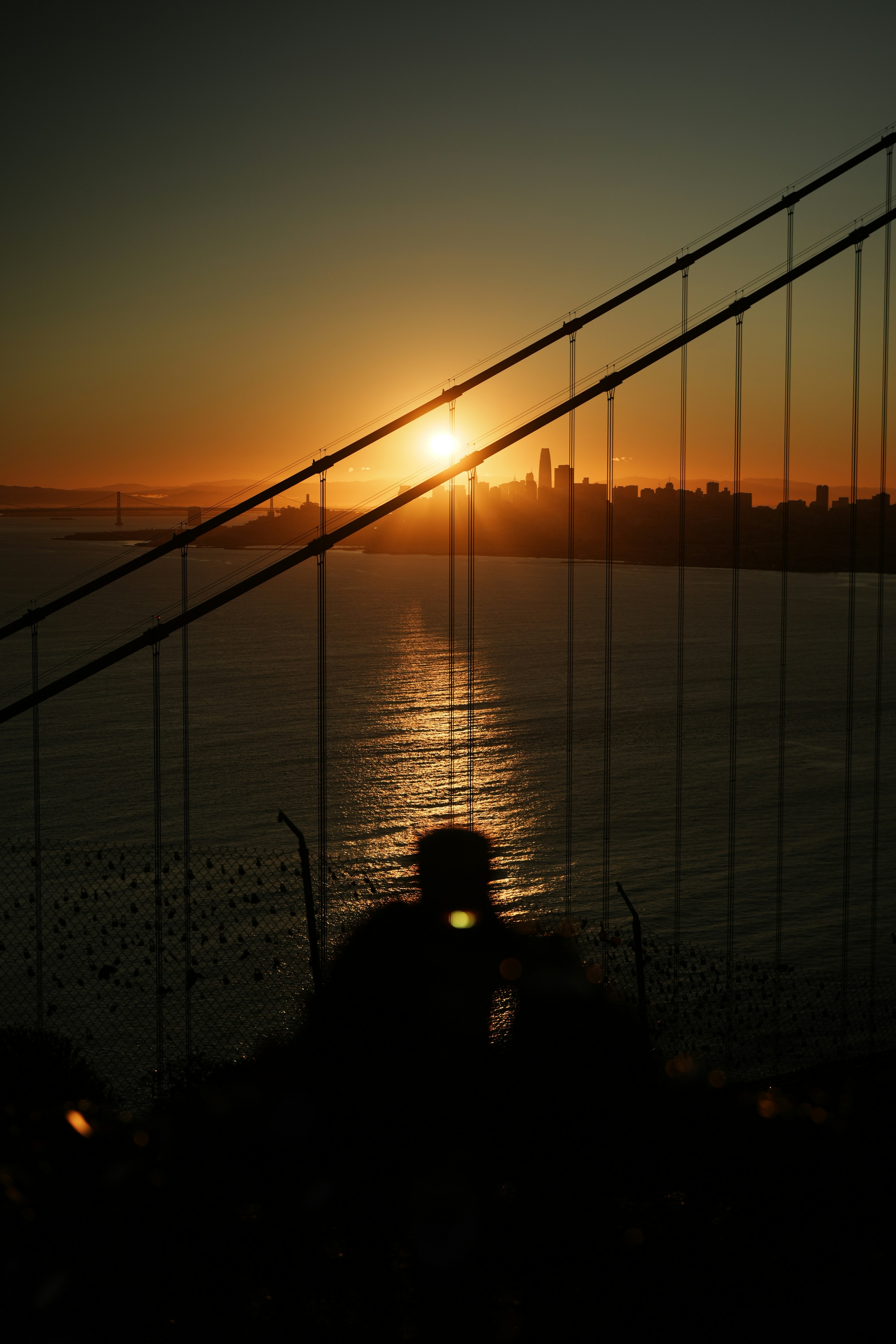 Silhouette of person against golden gate bridge and sunset.