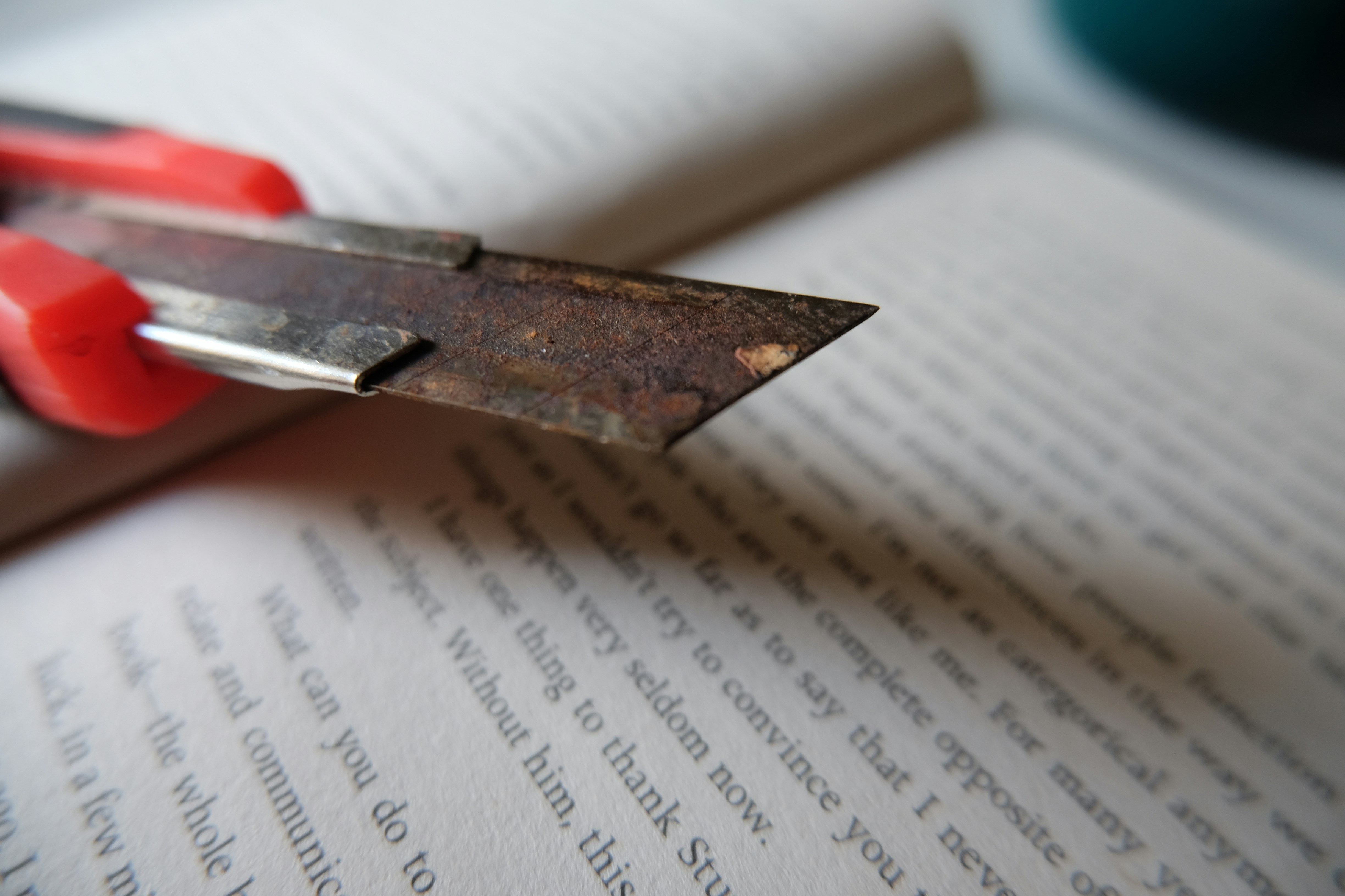 A rusty utility knife on an open book