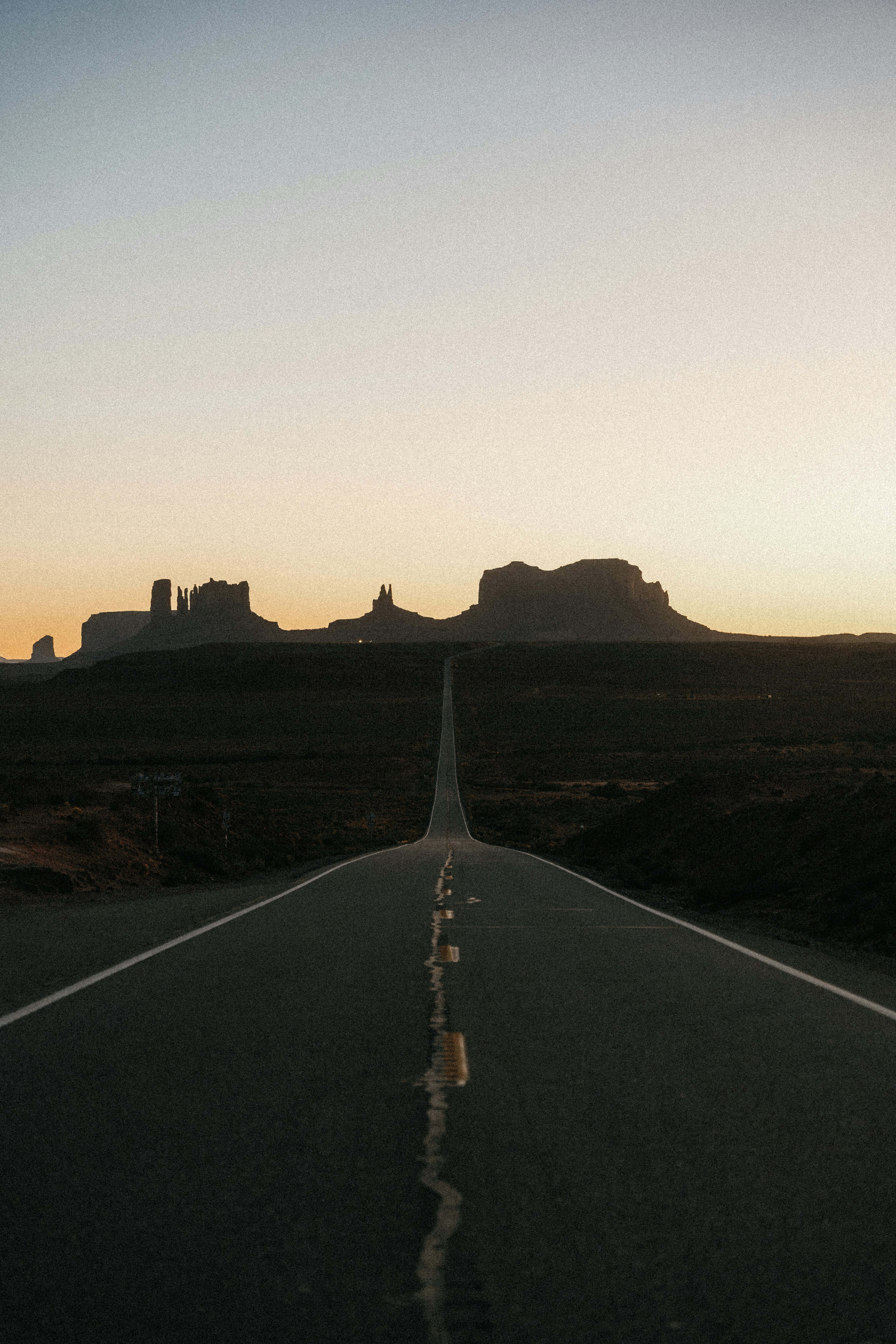 Desert highway leading to monument valley at sunset.