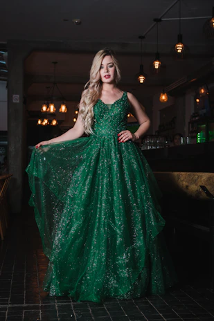 A woman in a sparkling green evening gown in a dimly lit restaurant.