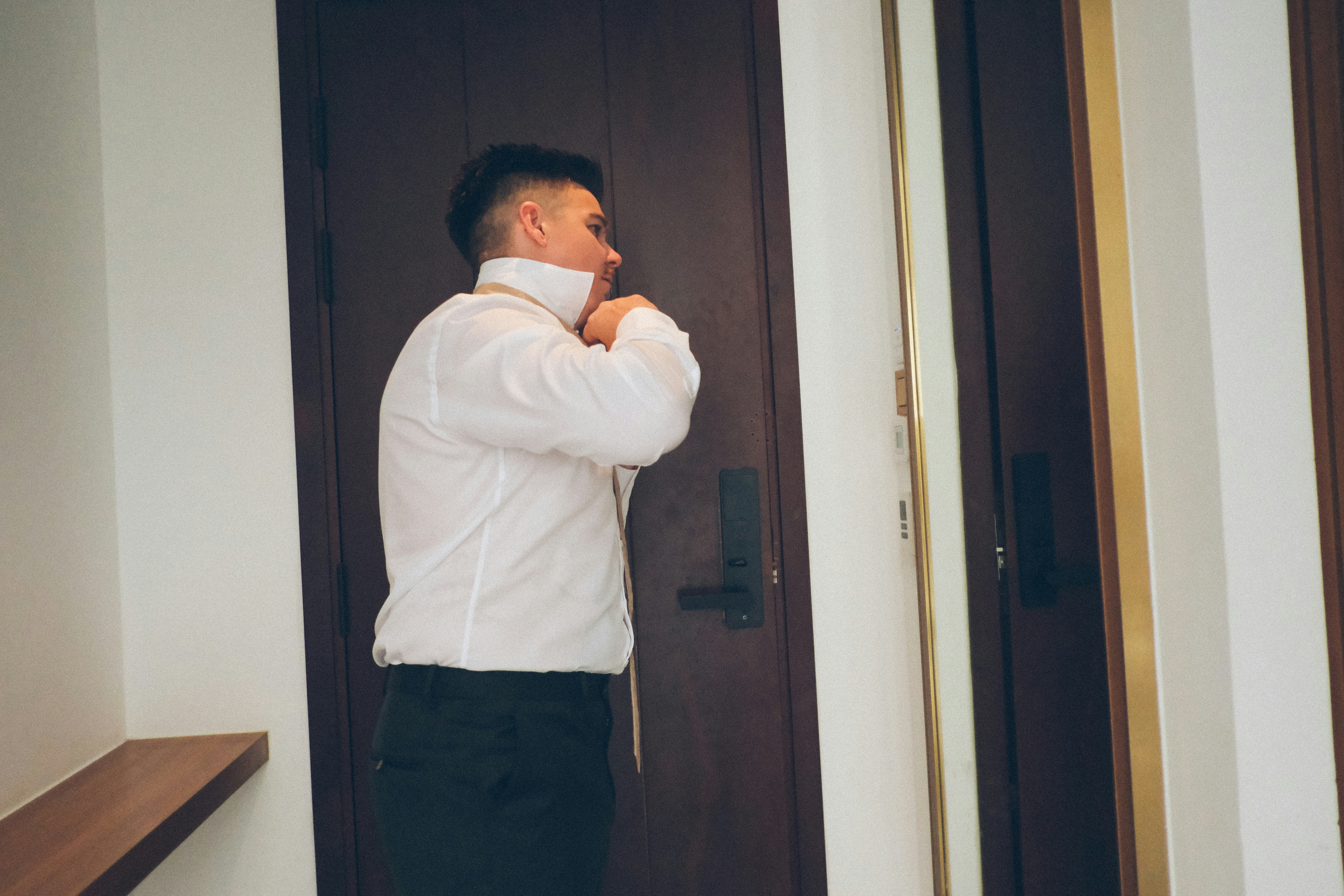 Man in white shirt buttons collar in hotel room