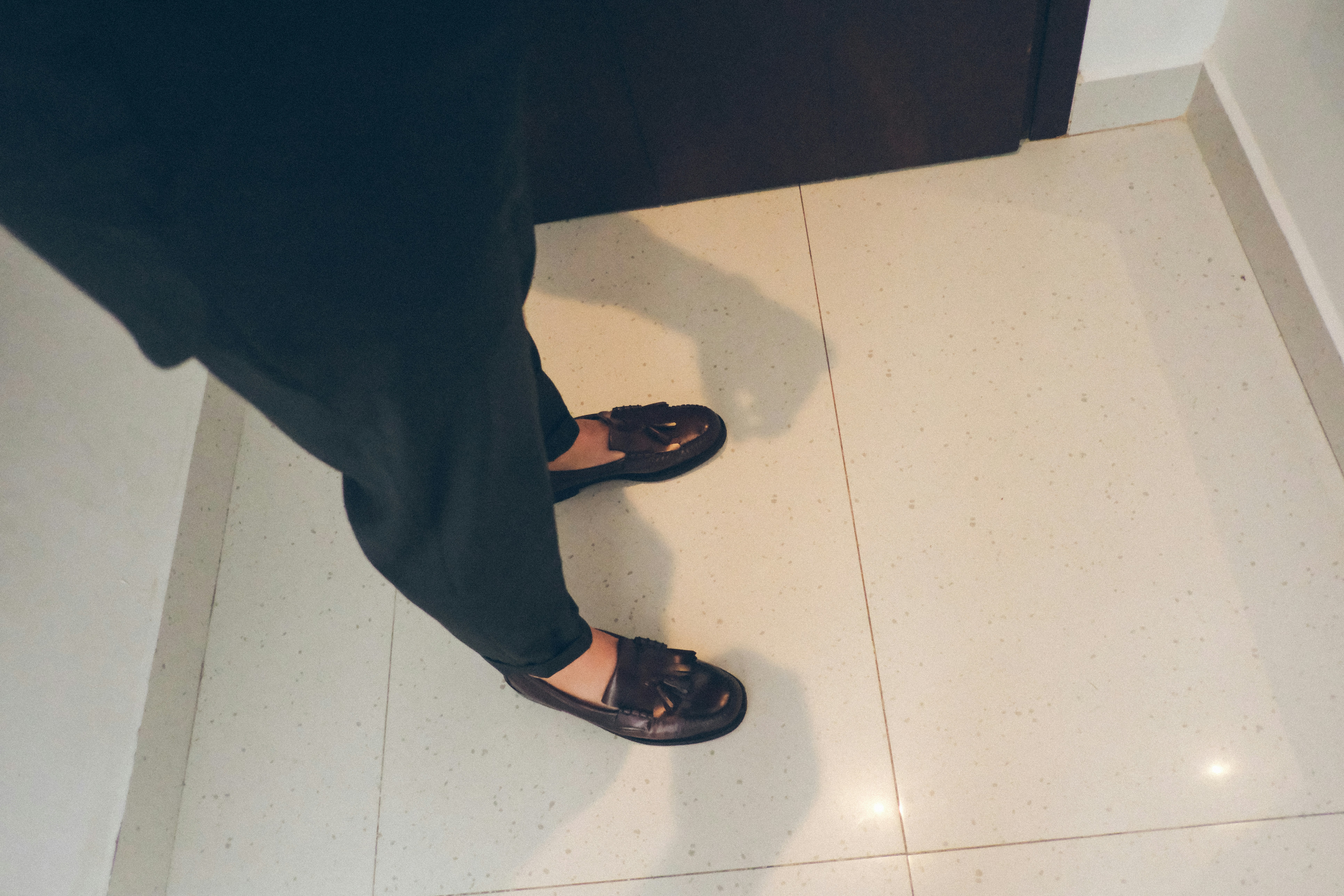 Person wearing black pants and loafers on tiled floor
