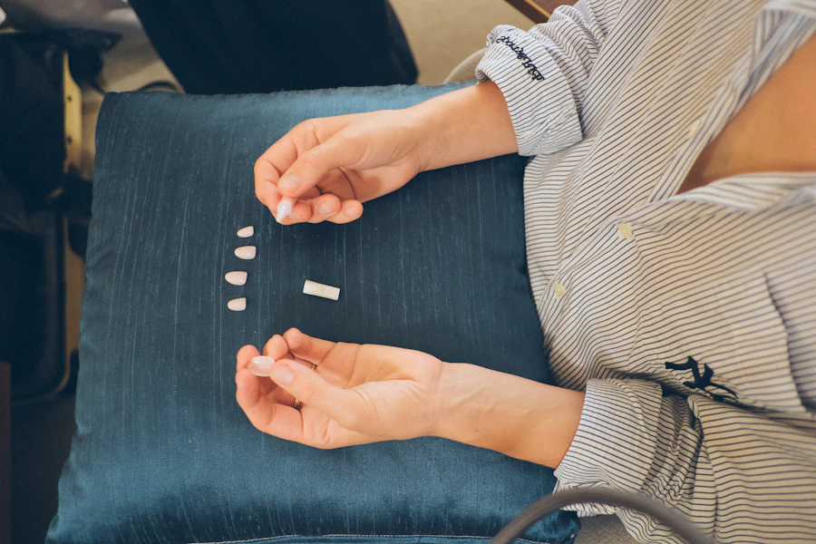 Person's hands arranging small white pills on a cushion.