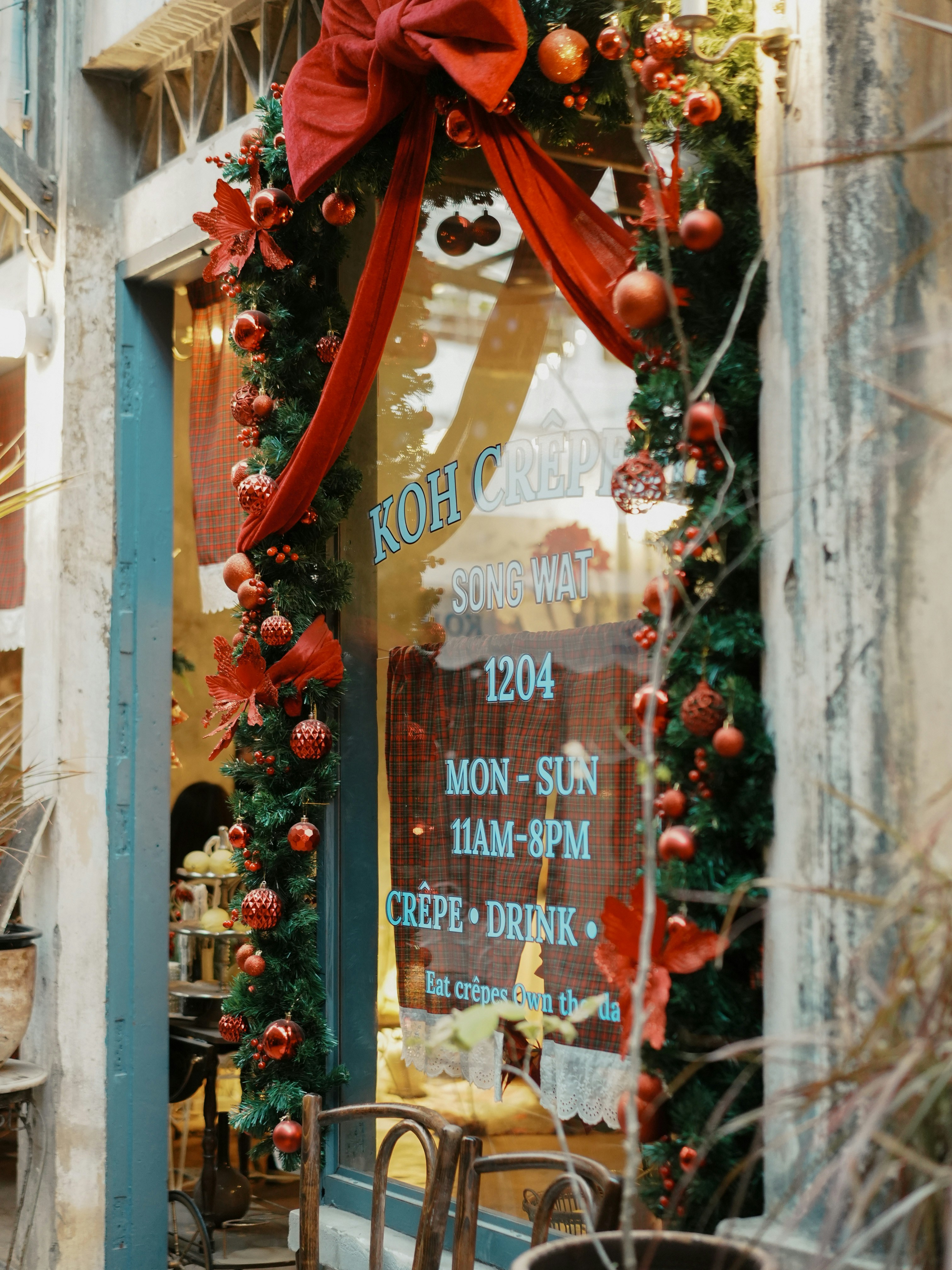 Ladenfront, dekoriert mit Weihnachtsornamenten und roten Schleifen.