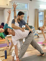 Yoga instructor assists student in triangle pose.