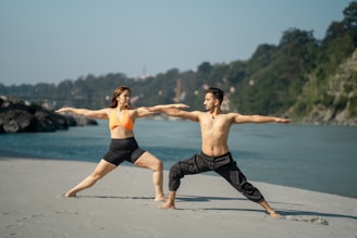 Couple practicing yoga warrior pose by the river