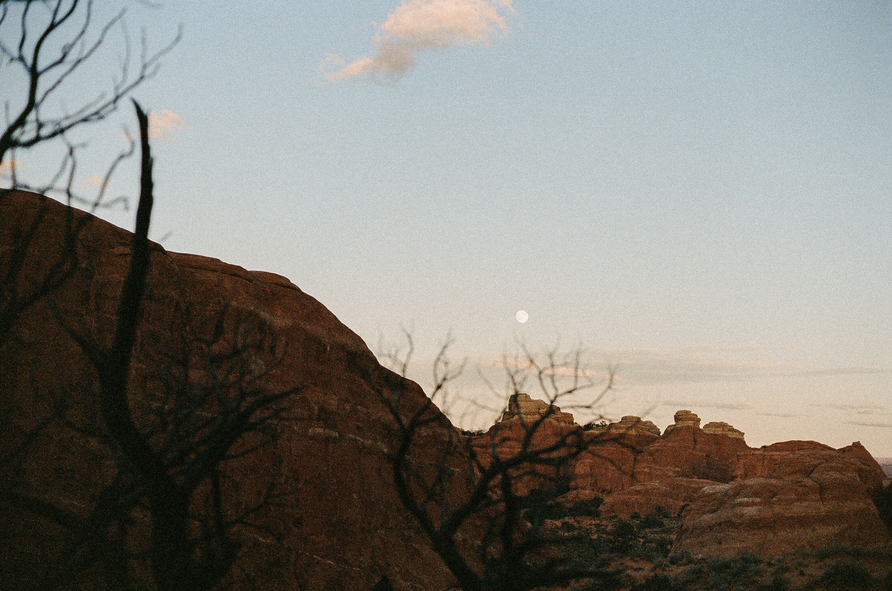 Rocky landscape with a full moon in the sky.