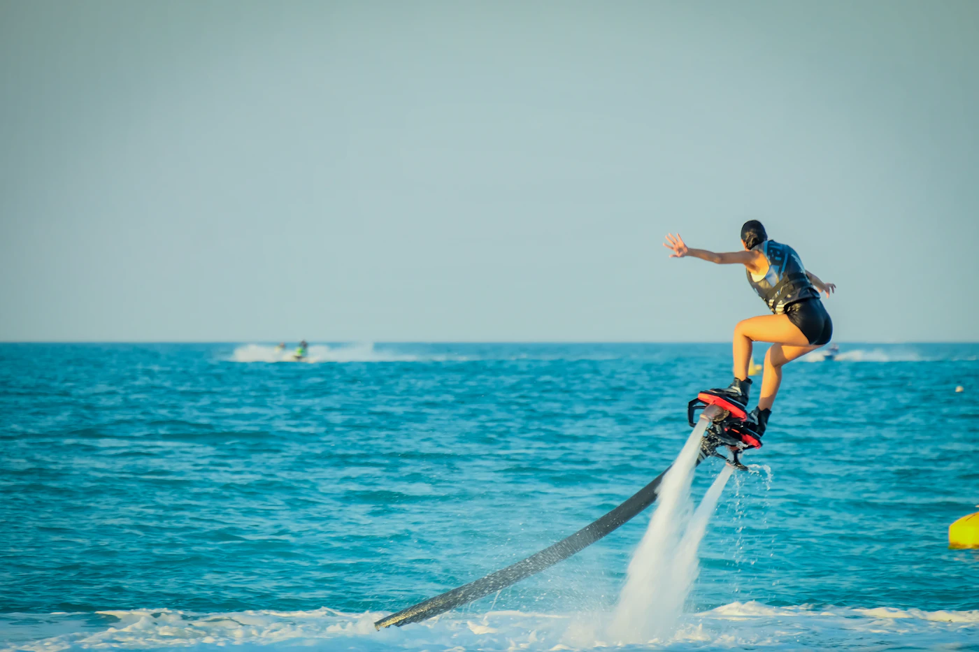 A flyboarder hovering above turquoise water on twin jets of water