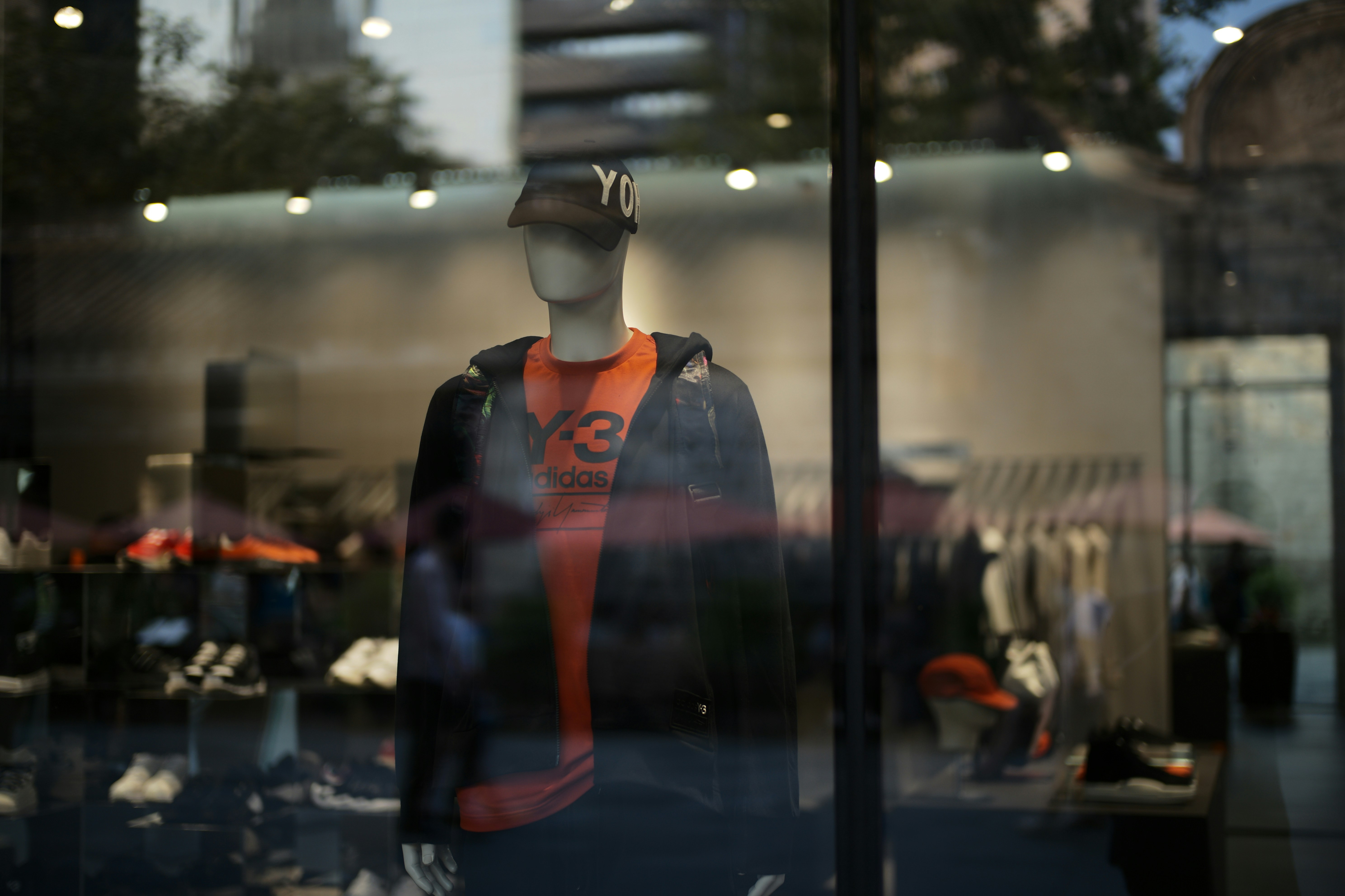 Mannequin in store window wearing orange shirt and jacket