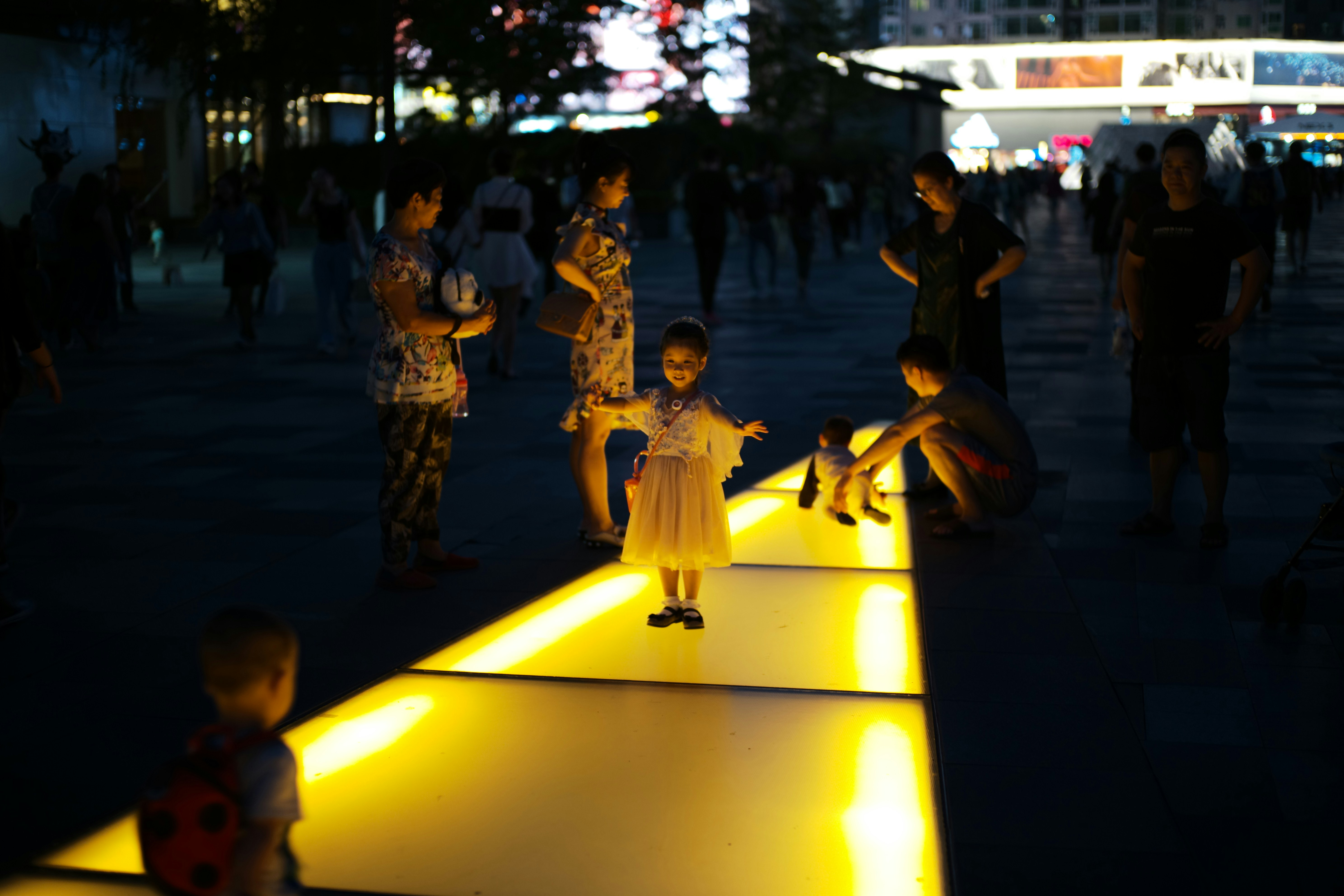 Children play on illuminated pathway at night