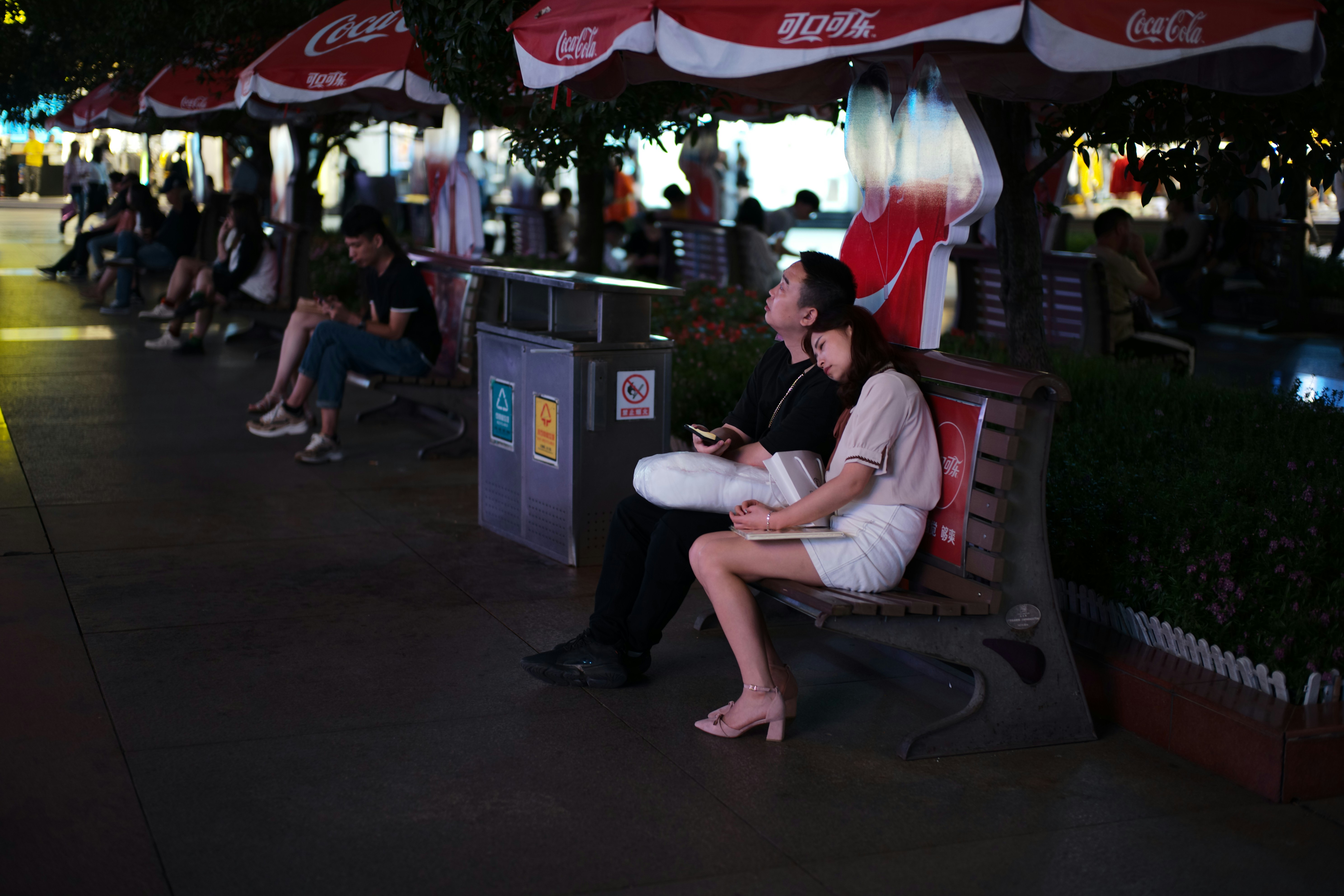 Couple resting on bench under umbrellas at night