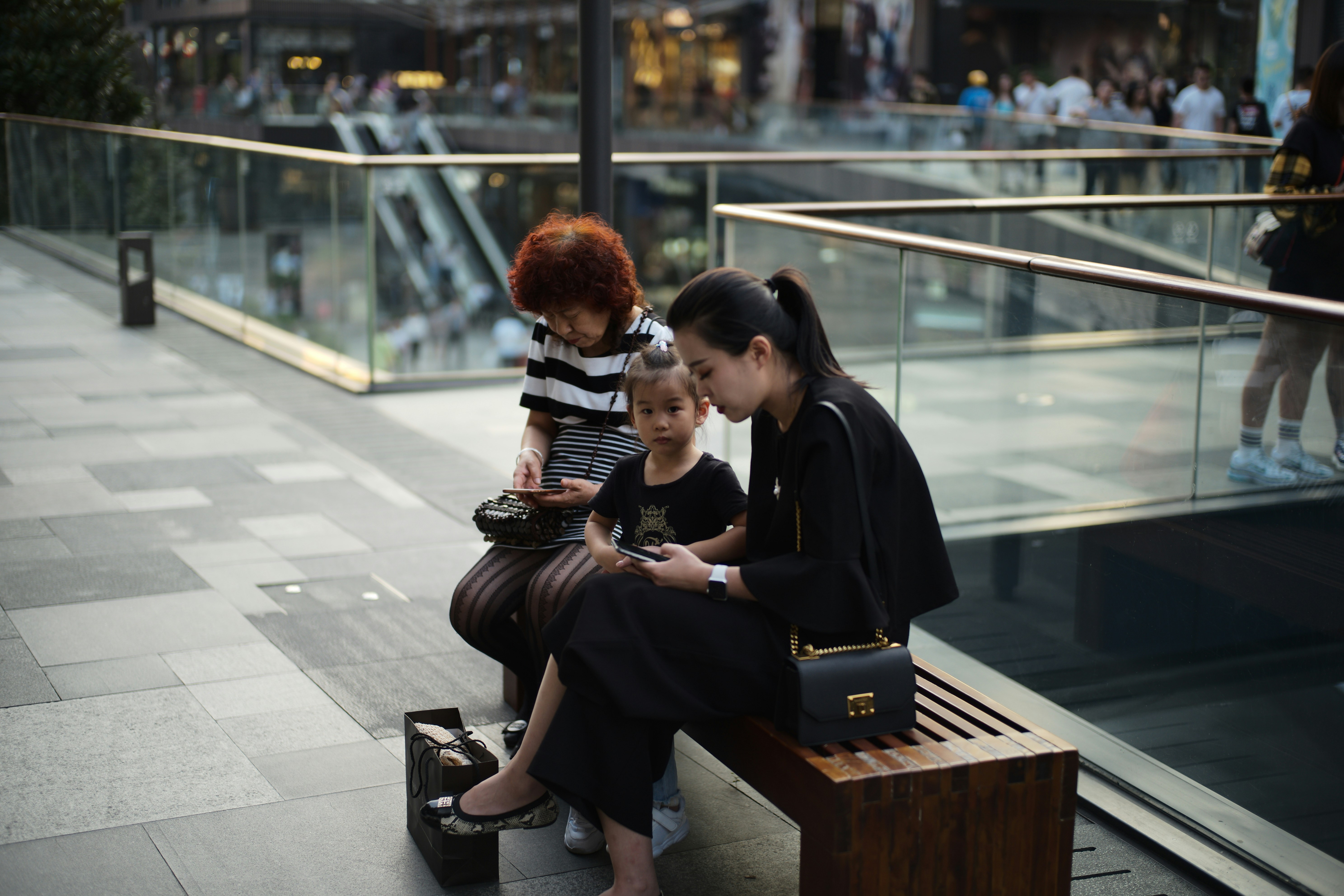 Woman and child looking at phone on a bench.