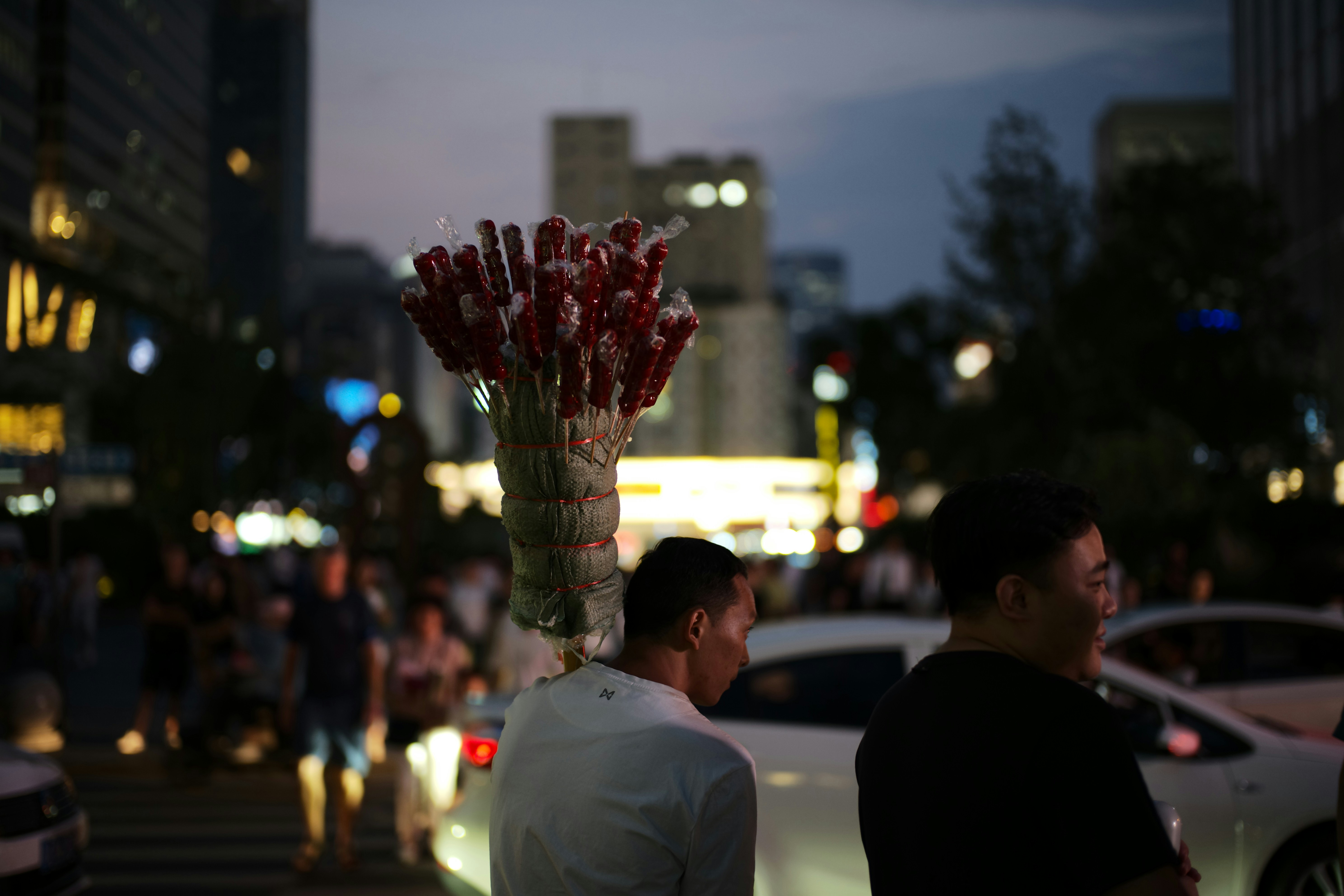 Street vendor with a bundle of items at dusk.