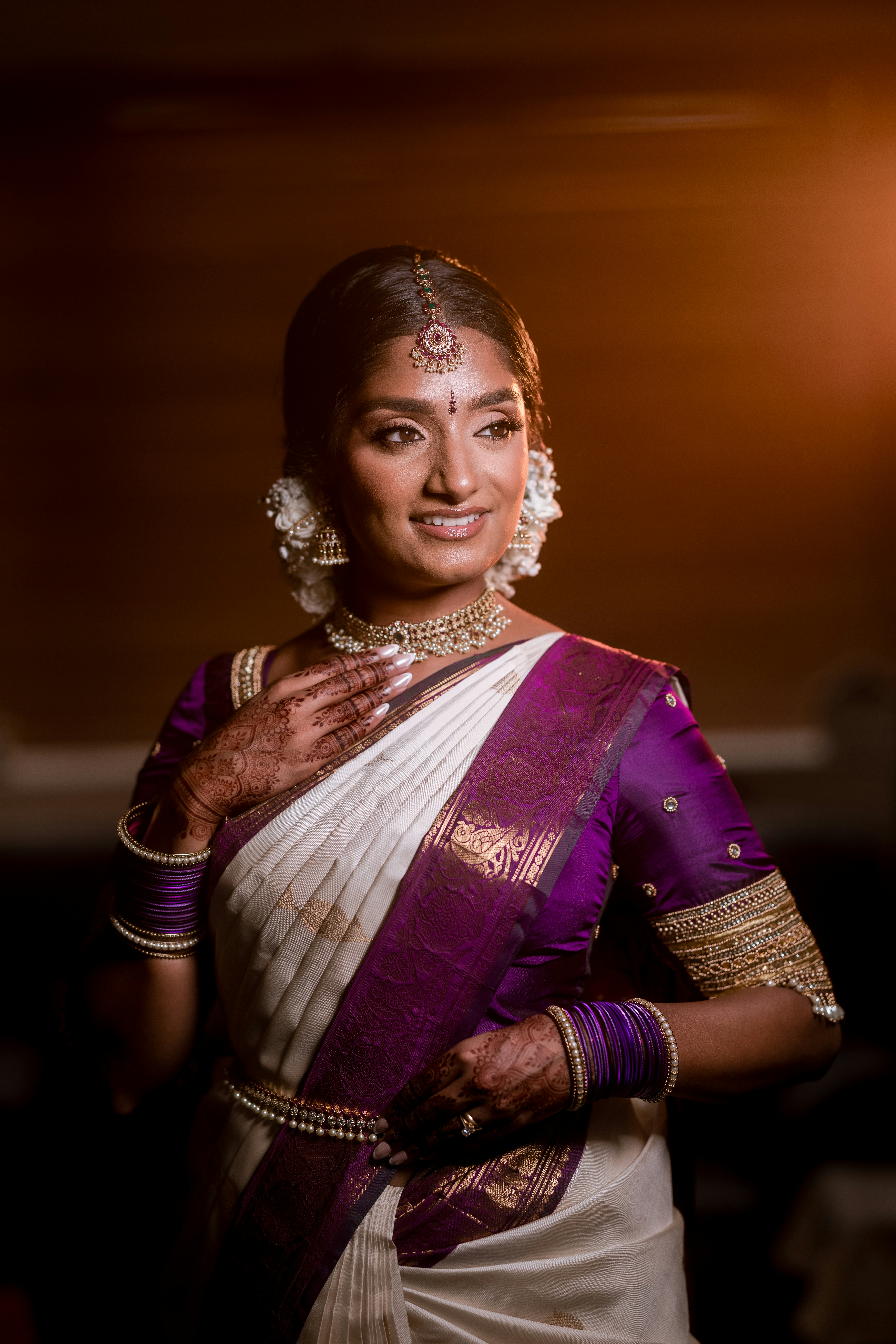 A bride in a white and purple saree smiles