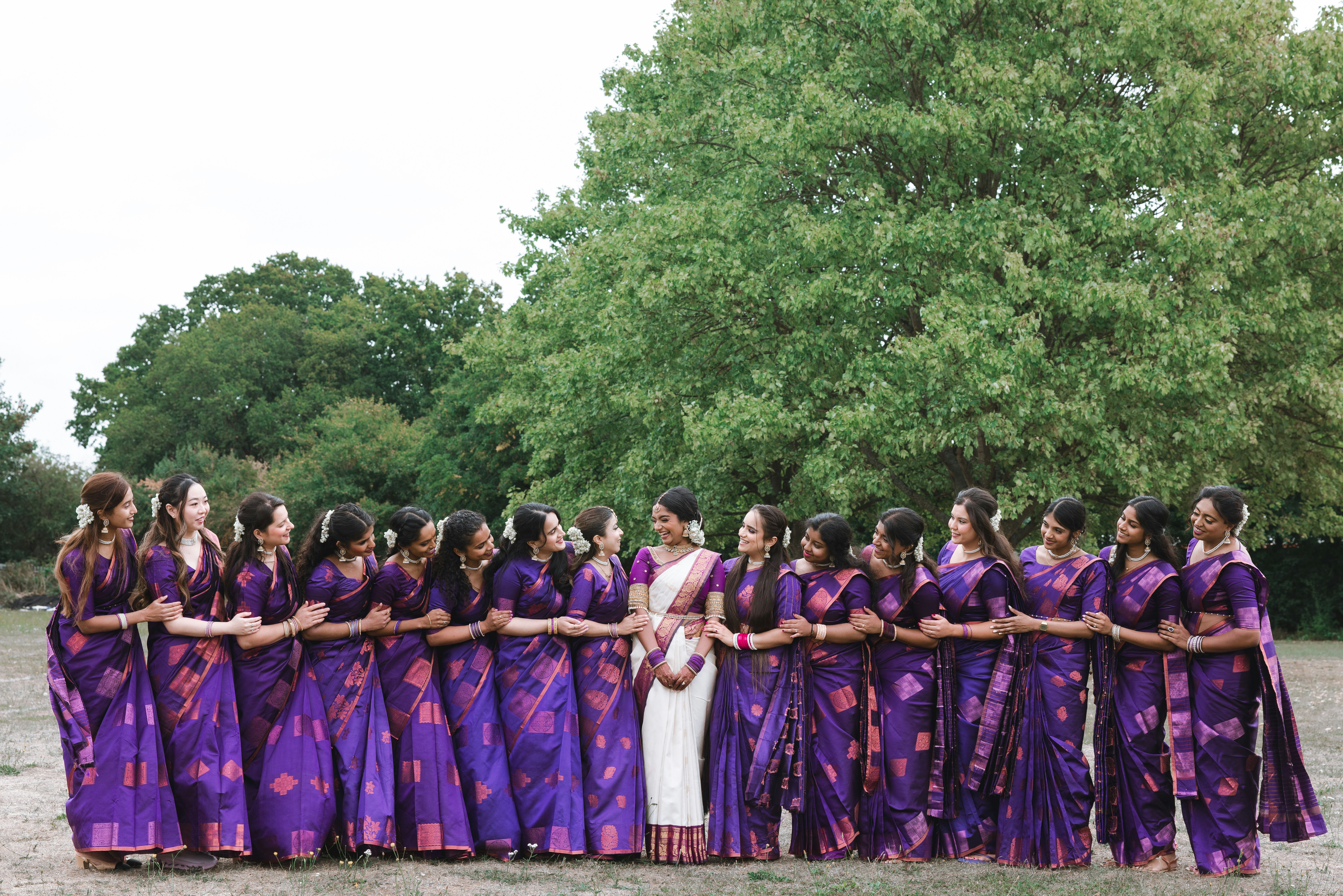Group of women in purple sarees standing in a circle